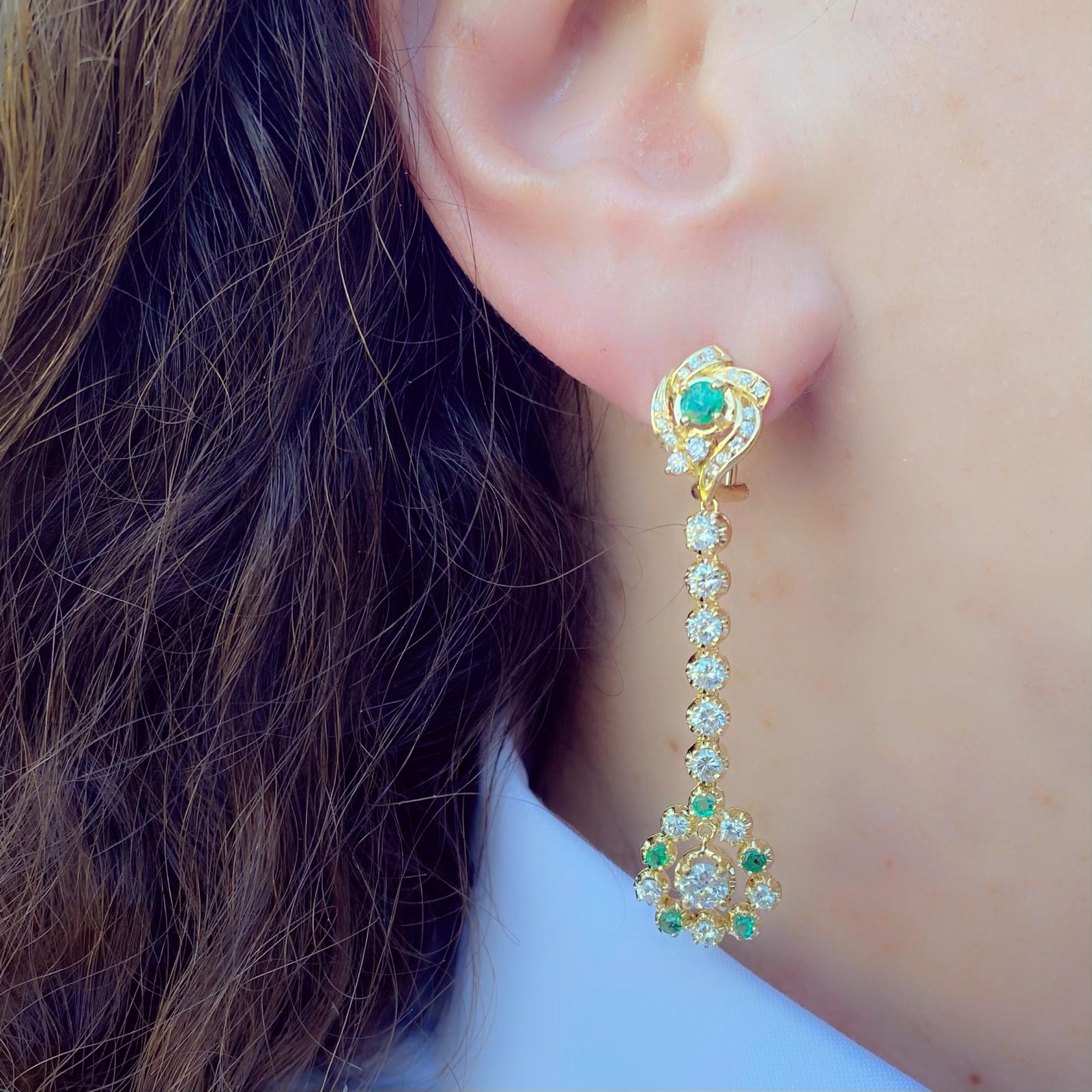 These 18k gold drop earrings are elegant and playful! Set with 58 round-cut diamonds, G-H/VS-SI, weighing approximately 3.00 carats, and highlighted by round-cut emeralds. The earrings weigh 12.7 grams and measure 2 1/4 inches long. They sparkle as