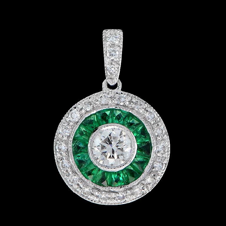 This stunning Art Deco pendant features genuine Emerald and Diamond in 18 Karat White Gold.
This beautiful Diamond in the center size 4 mm. set in 0.26 Carat is surrounded by 14 pieces of French cut Emerald totaling 0.63 Carat.
It is accented by