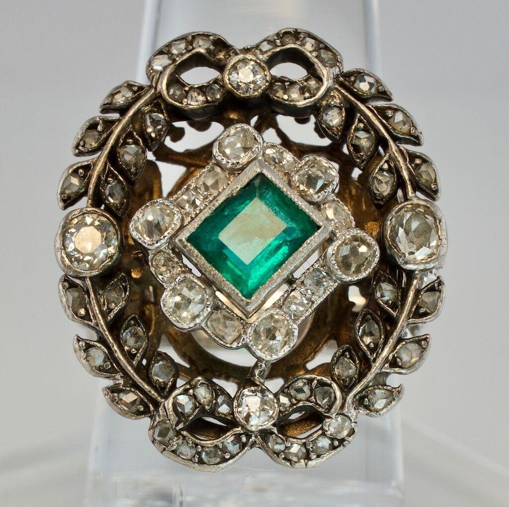 This stunning antique ring is finely crafted in solid 14K White Gold and set with genuine Earth mined Emerald and diamonds. The center bezel-set Emerald measures 5mm x 4.5mm (about .35 carat). This is a very clean and transparent gem with amazing