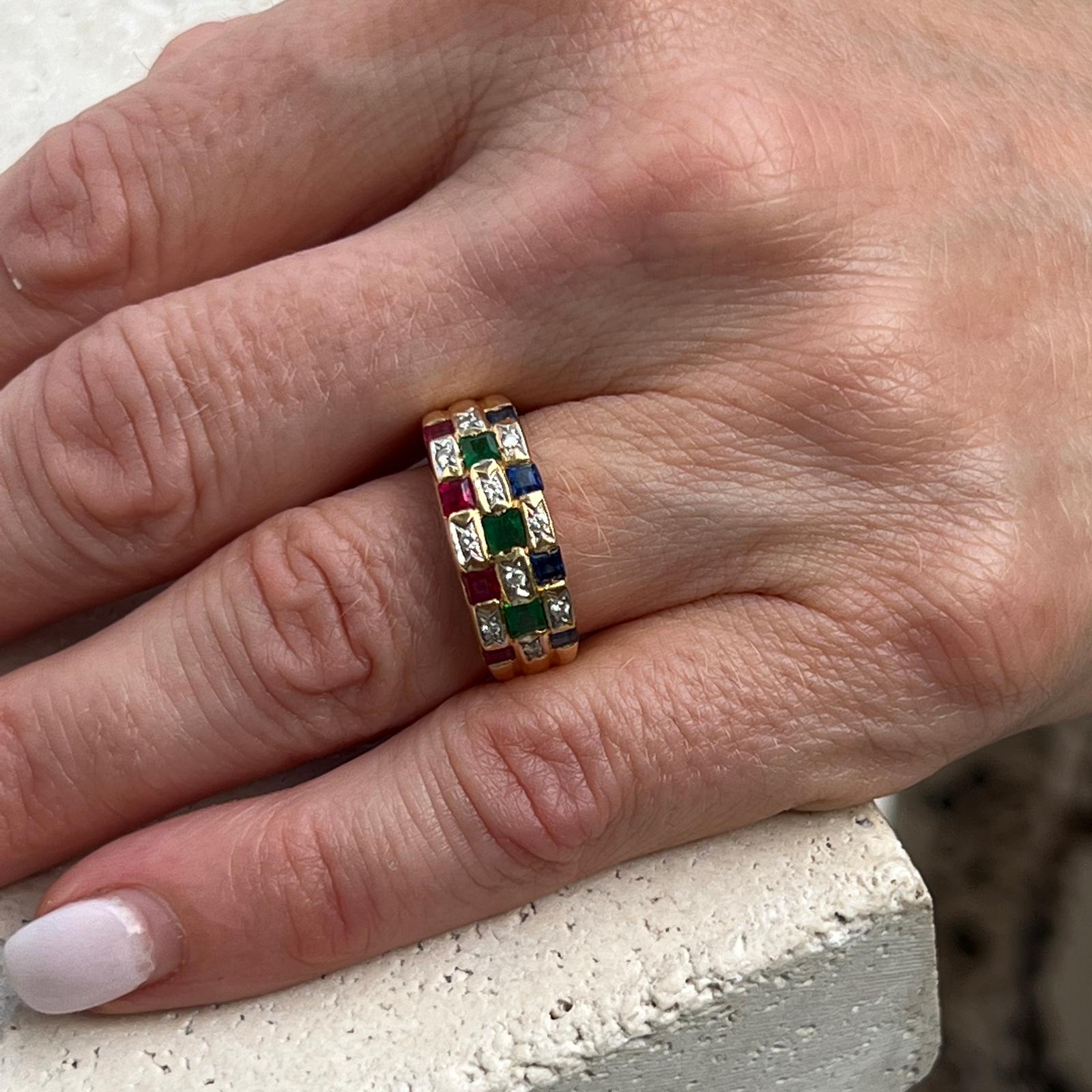 Diamond and colorful precious gemstone checkerboard ring crafted in 18 karat yellow gold. The ring features diamonds, rubies, sapphires, and emeralds. The 10 round briliant cut diamonds weigh approximately .10 CTW. The band measures 8mm in width and
