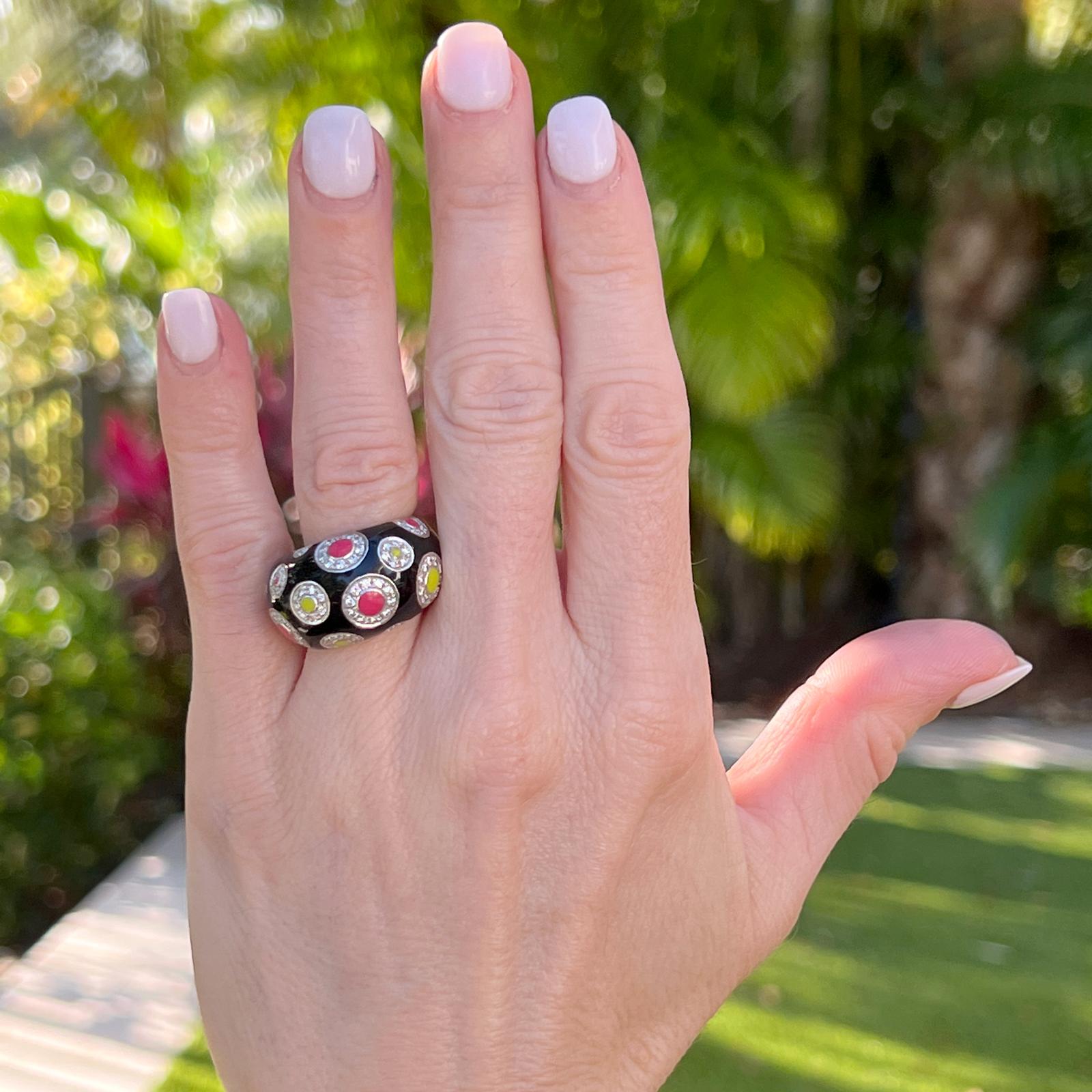 Diamond and enamel band ring fashioned in 18 karat white gold. The ring features a black enamel background with diamond pink and lime green colorful dot design. The diamonds weigh approximately 1.00 CTW and are graded G-H color and SI clarity. The