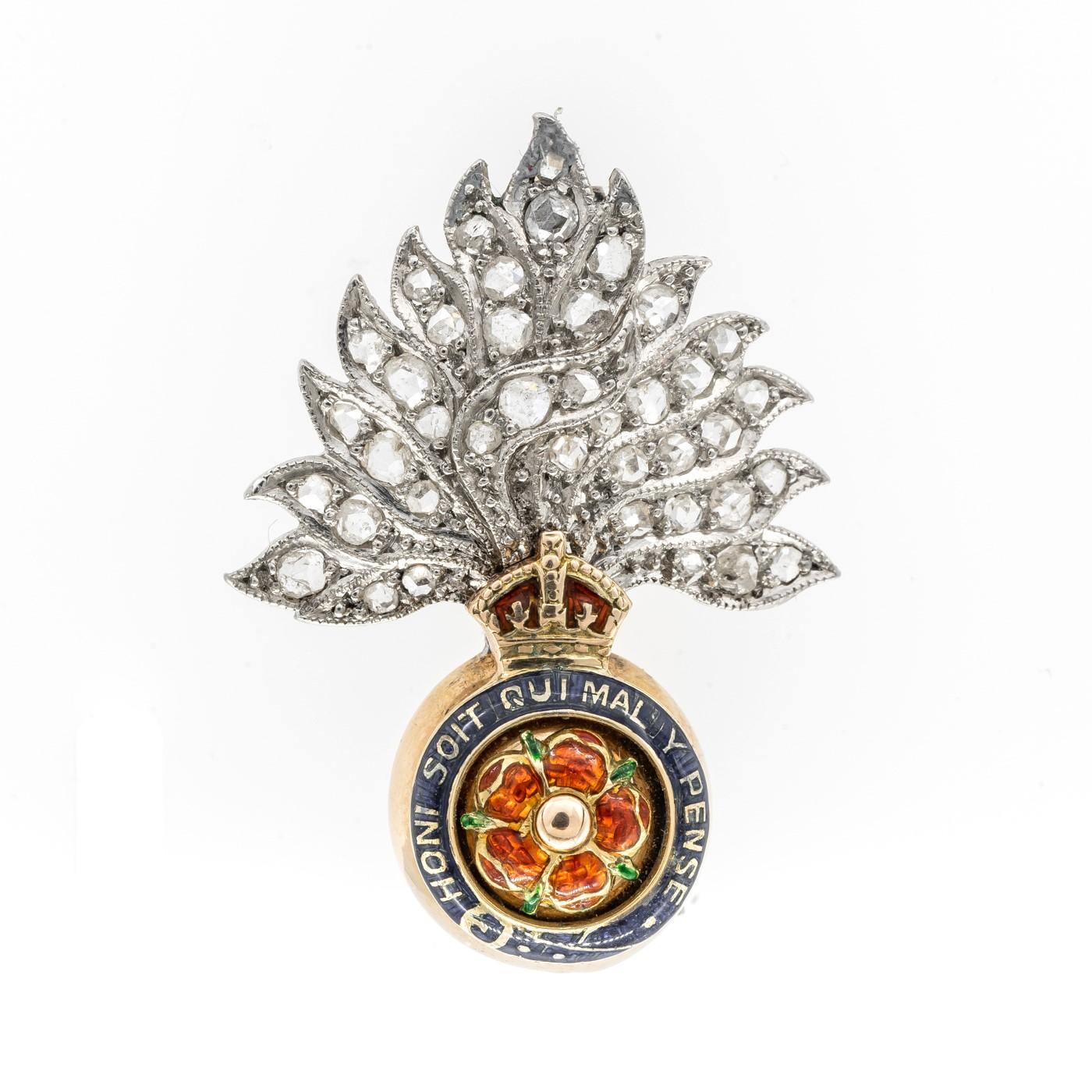 A British Royal Fusiliers badge, with a rose-cut diamond set flame, on platinum, over an enamelled crown, surmounting a blue enamelled garter, inscribed HONI SOIT QUI MAL Y PENSE, surrounding an enamelled red rose on yellow gold. Honi soit qui mal y