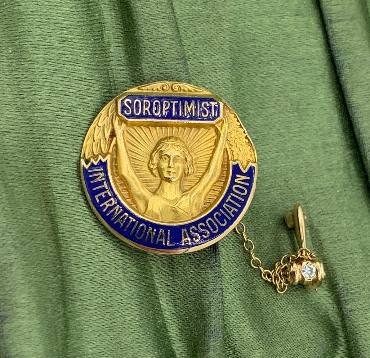 This is a wonderful antique Brooch and Pin from the Soroptomist International Society with an image of a woman with outstretched arms in front of a blazing sun. The brooch is a piece of early history from the Women's Movement!  The larger pin is
