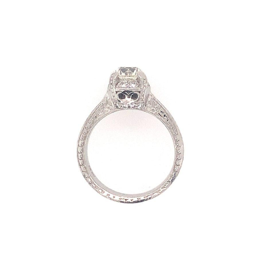 One diamond engagement ring in platinum centering one old European cut diamond weighing approximately 1.35 ct. with K-L color and VS-2 clarity. The vintage style ring featuring hand engraved details and is enhanced with 16 round brilliant cut