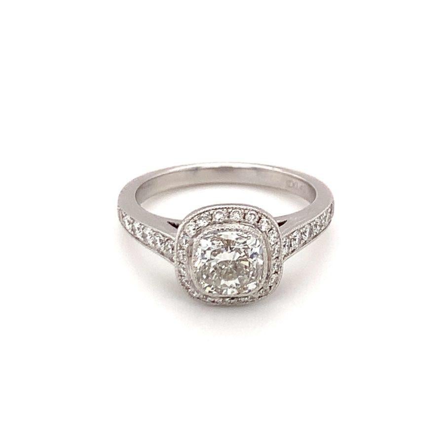 Diamond designer halo-style engagement ring centering one bezel set, cushion brilliant cut diamond weighing 1.14 ct., G-H color and SI-2 clarity. Enhanced by 0.35 ct. in accent diamonds and milgrain edging. 

Intriguing, splendid,