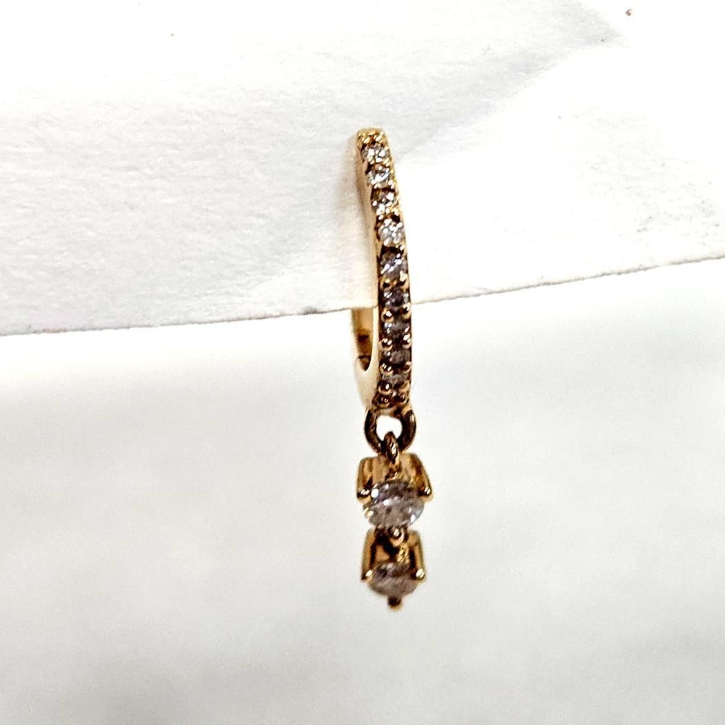 Questo elegante mini cerchio con diamante eternity a doppio penzolo è realizzato in oro giallo 14 carati e progettato per aggiungere un movimento sottile e uno scintillio raffinato a qualsiasi orecchio. Il cerchio presenta dodici diamanti rotondi