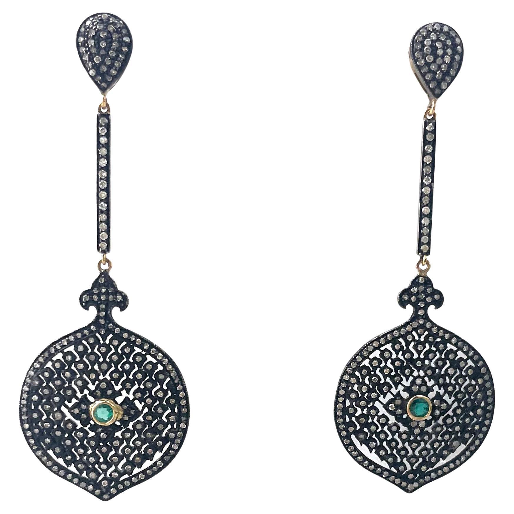 Description
Delicate diamond studded openwork filigree black earring, accented with a vibrant green Emerald center. The beautiful filigree medallions are suspended from a pave diamond bar and pear shape ear post. Item #E3129

Materials and