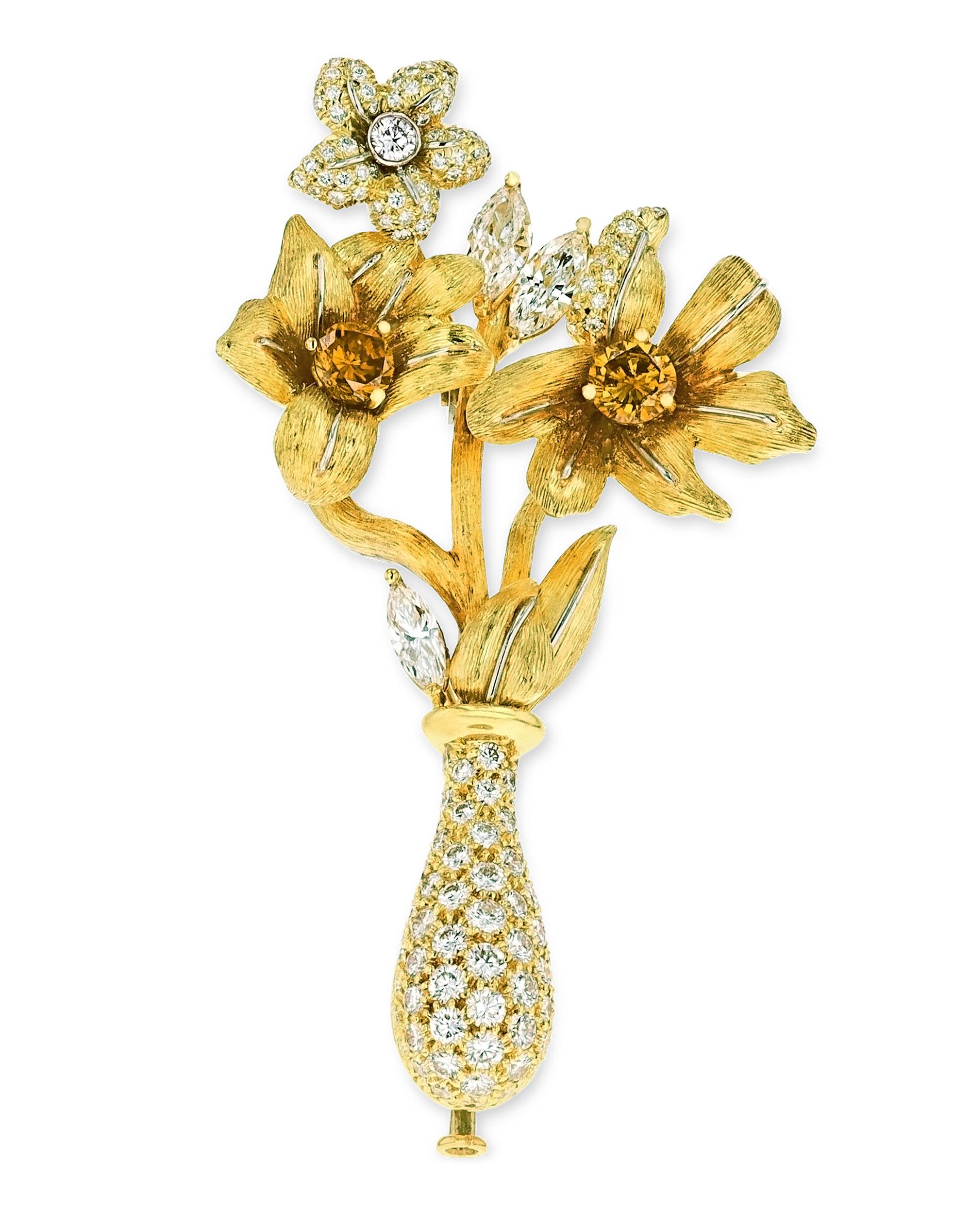 This sophisticated brooch from the famed American jeweler Henry Dunay takes the form of a bouquet of beautiful amaryllis flowers. Two colored diamonds totaling approximately 1.00 carat form the center of the two largest flowers, while 4.50 carats of