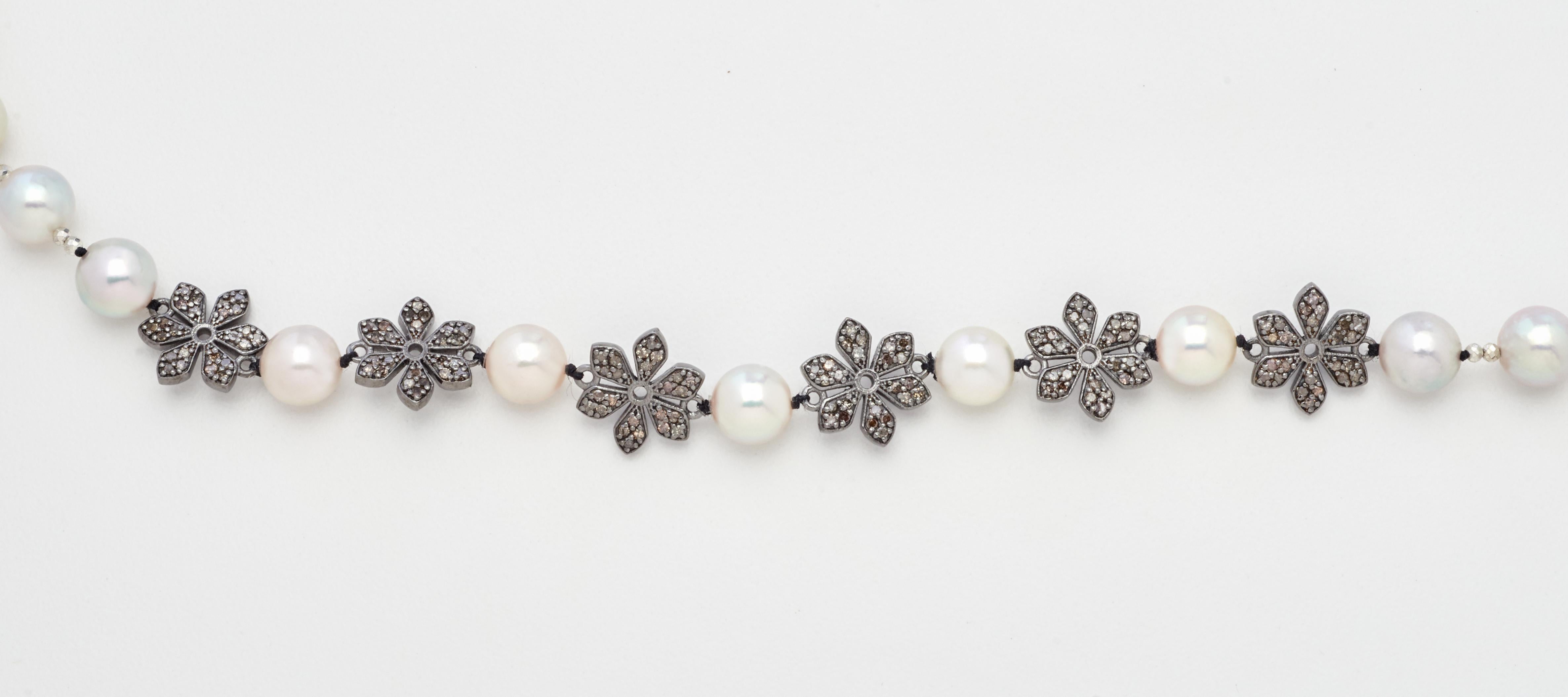 Six sparkling diamond encrusted sterling silver floral charms are the feature of this new design. Complimented by genuine white lustrous Akoya pearls, this bright 23 inch strand is a beautiful addition to any collection. Hand-strung with thirty-nine