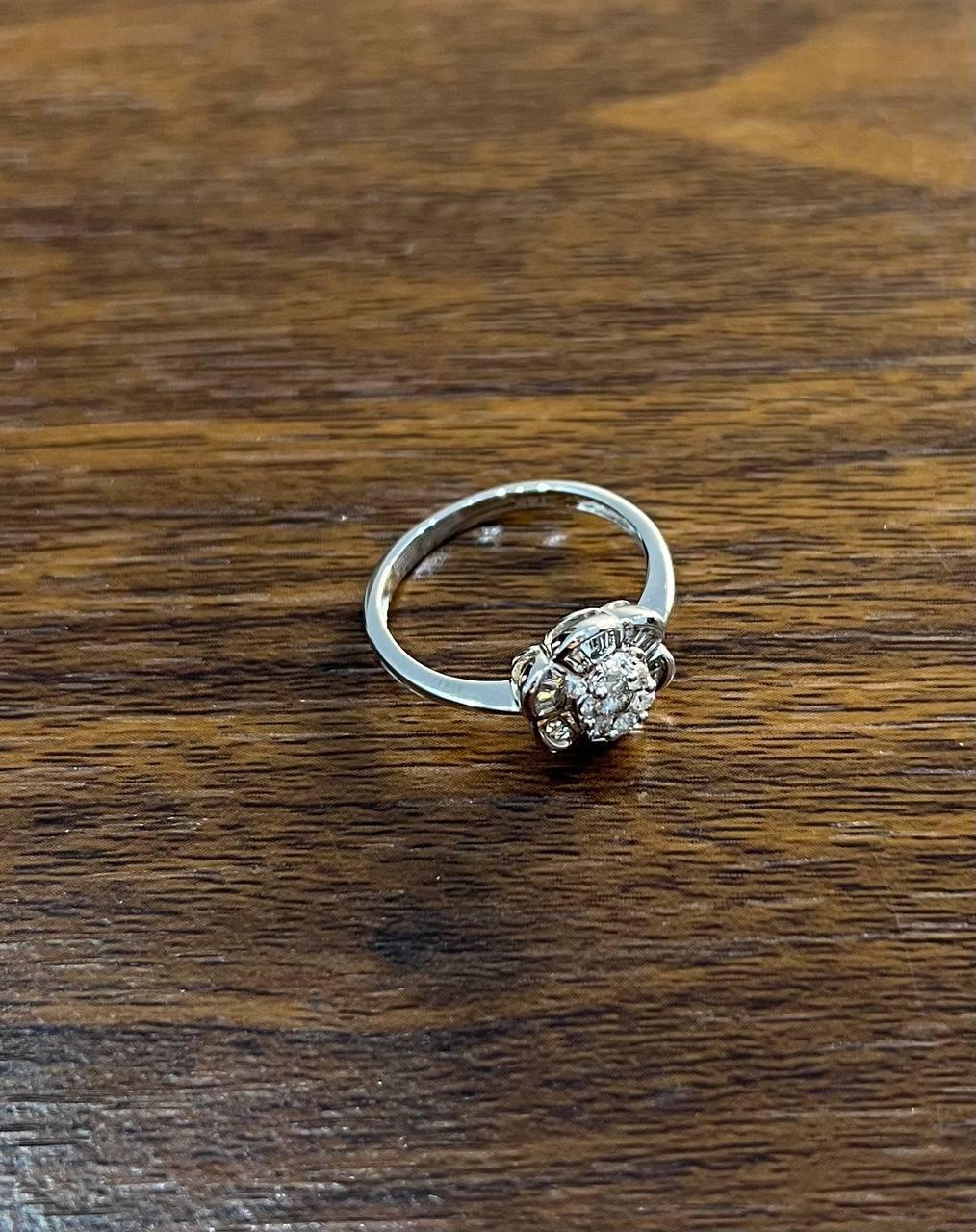 Discover the elegance with our exquisite ring. This captivating piece features a central round diamond, surrounded by a floral-inspired setting that enhances its brilliance. The intricate design showcases a harmonious blend of classic and