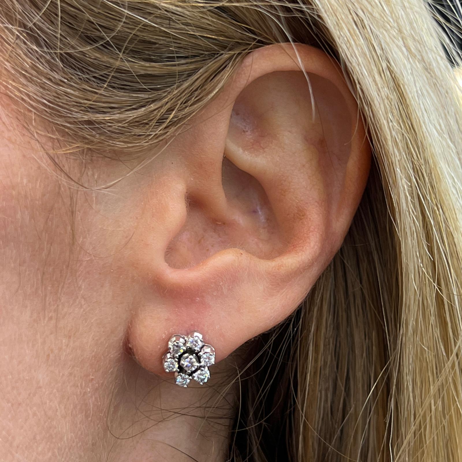 Diamond floral stud earrings fashioned in 18 karat white gold. The studs feature 14 round brilliant cut diamonds weighing .75 carat total weight and graded H-I color, SI clarity. The flowers measures 8.5mm in diameter, and are lightweight for