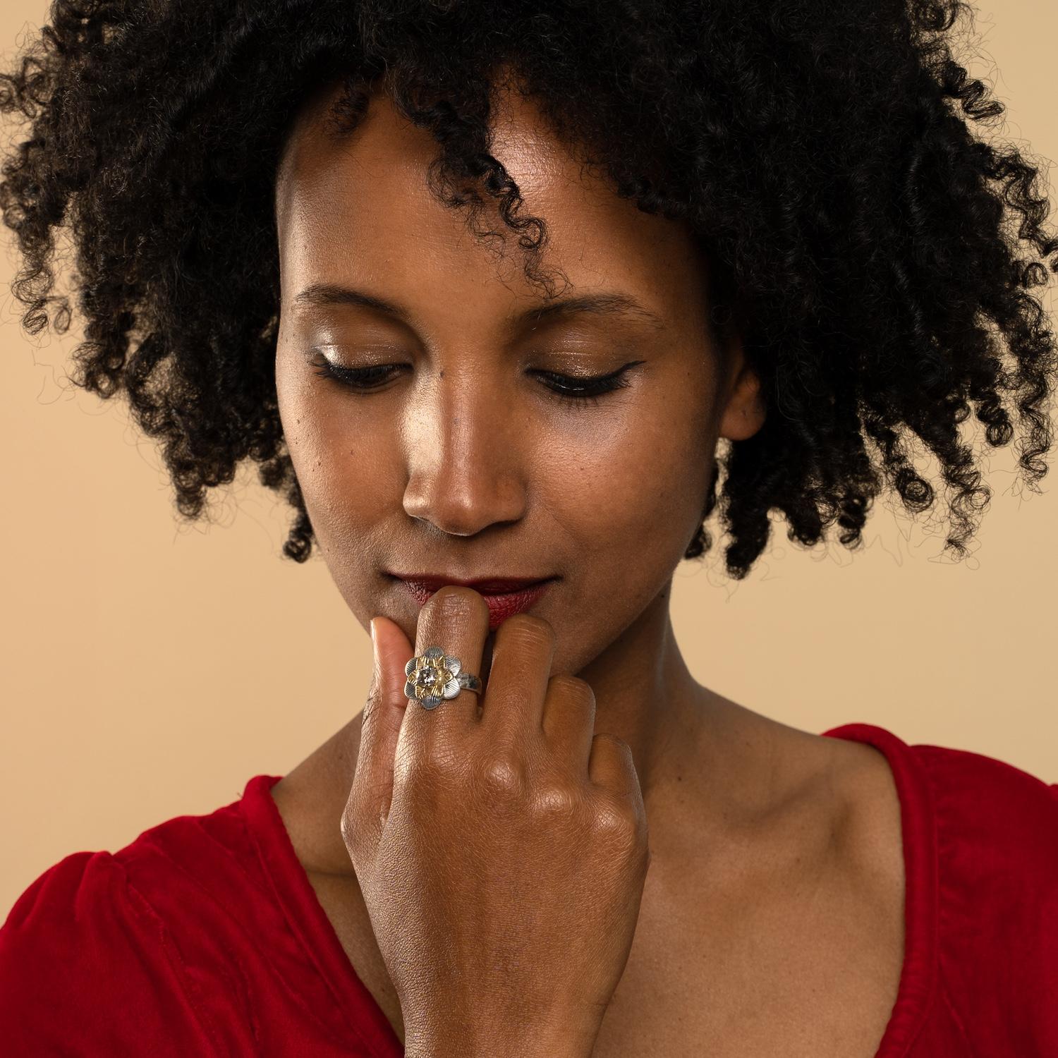 This one-of-a-kind diamond flower ring has been handmade in our workshops. It features an exceptional 0.93ct diamond which is set in hand-engraved 14ct gold. The rest of the ring is made in oxidized sterling silver, with a lightly hammered shank and