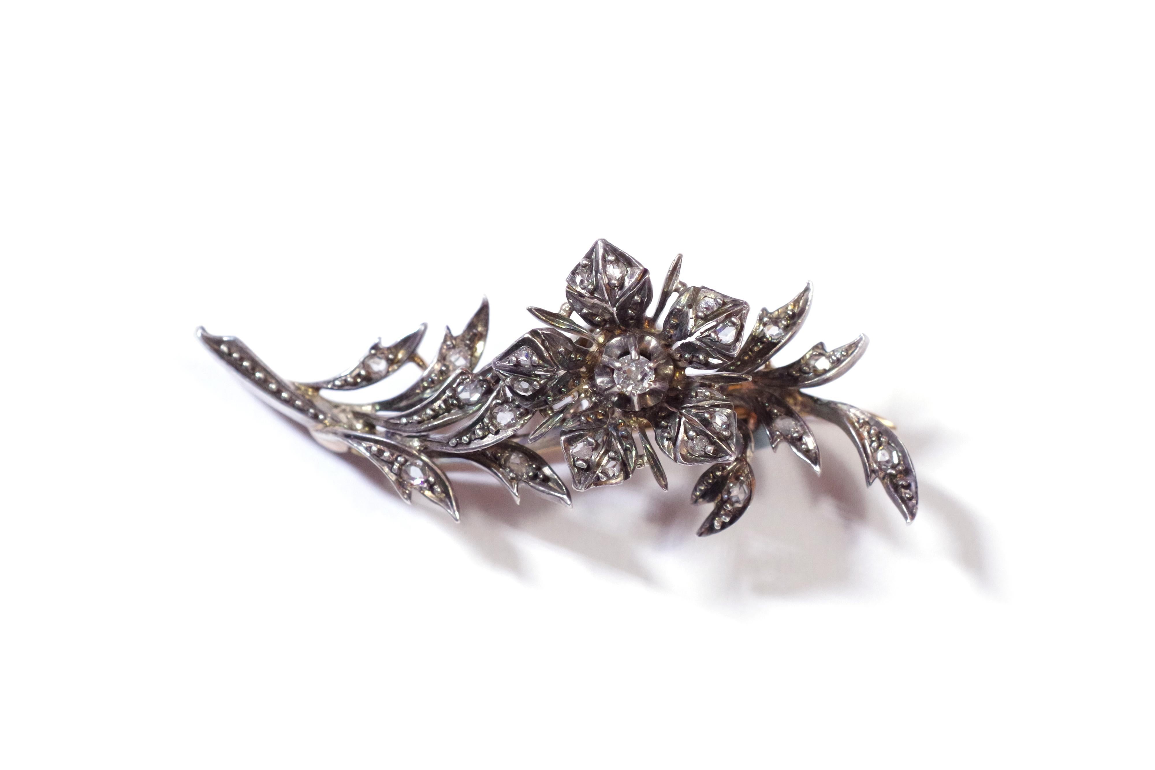 Diamond flower brooch tremblant in rose gold 18 karats and silver. Naturalist brooch representing a branch on which a flower is blooming. The flower is mounted on a spring which makes it vibrate when moved, hence the French name of the brooch 