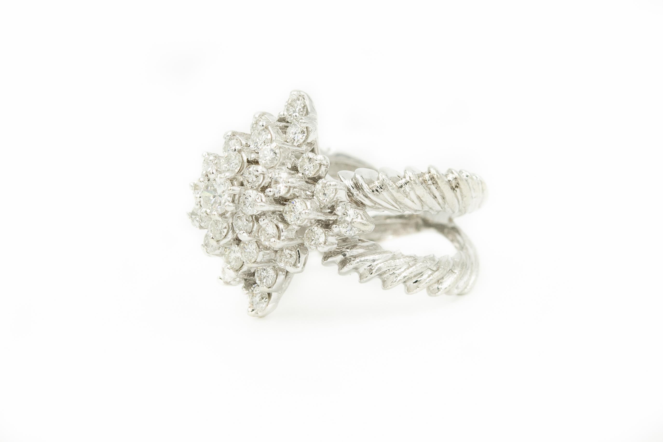 18k White gold flower or starburst diamond dome ring with a crossover notched band.  
US Ring size 5