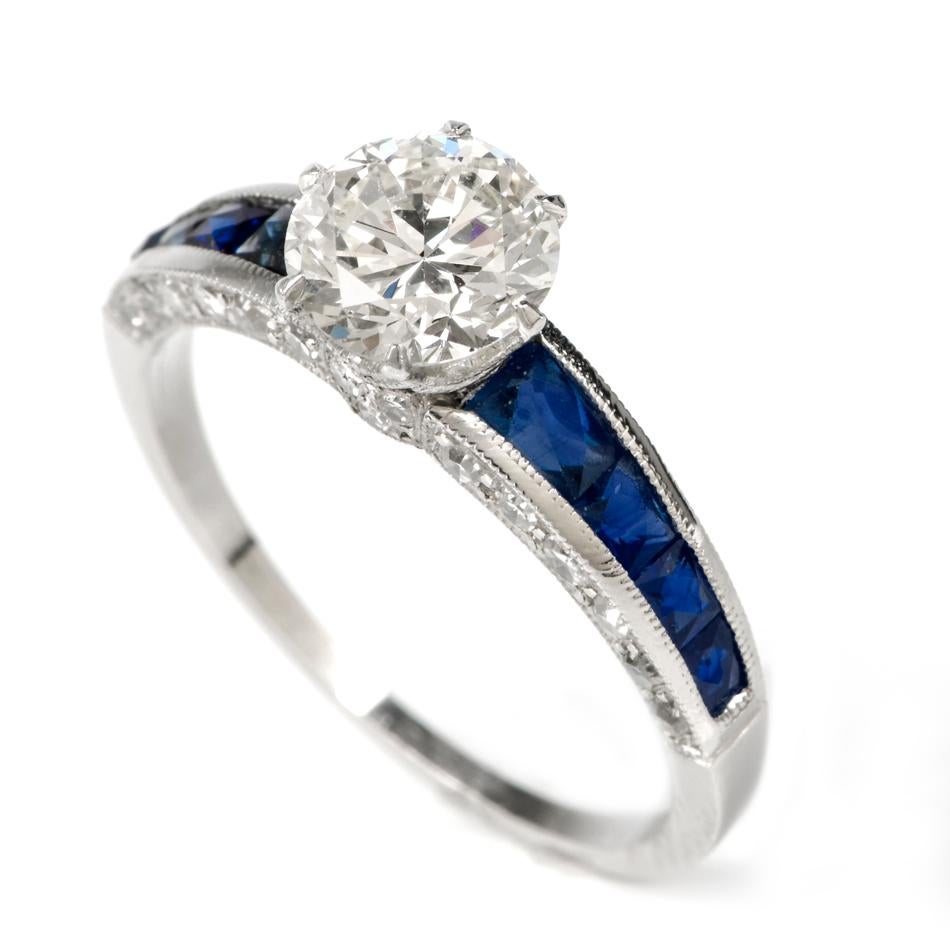 This stunning diamond and blue sapphire engagement ring is crafted in solid platinum weighing 3.4 grams and measuring 7mm high x 6mm. Showcasing a one stunning centered round-cut, prong set diamond, along with 32 smaller round-cut pave set diamonds