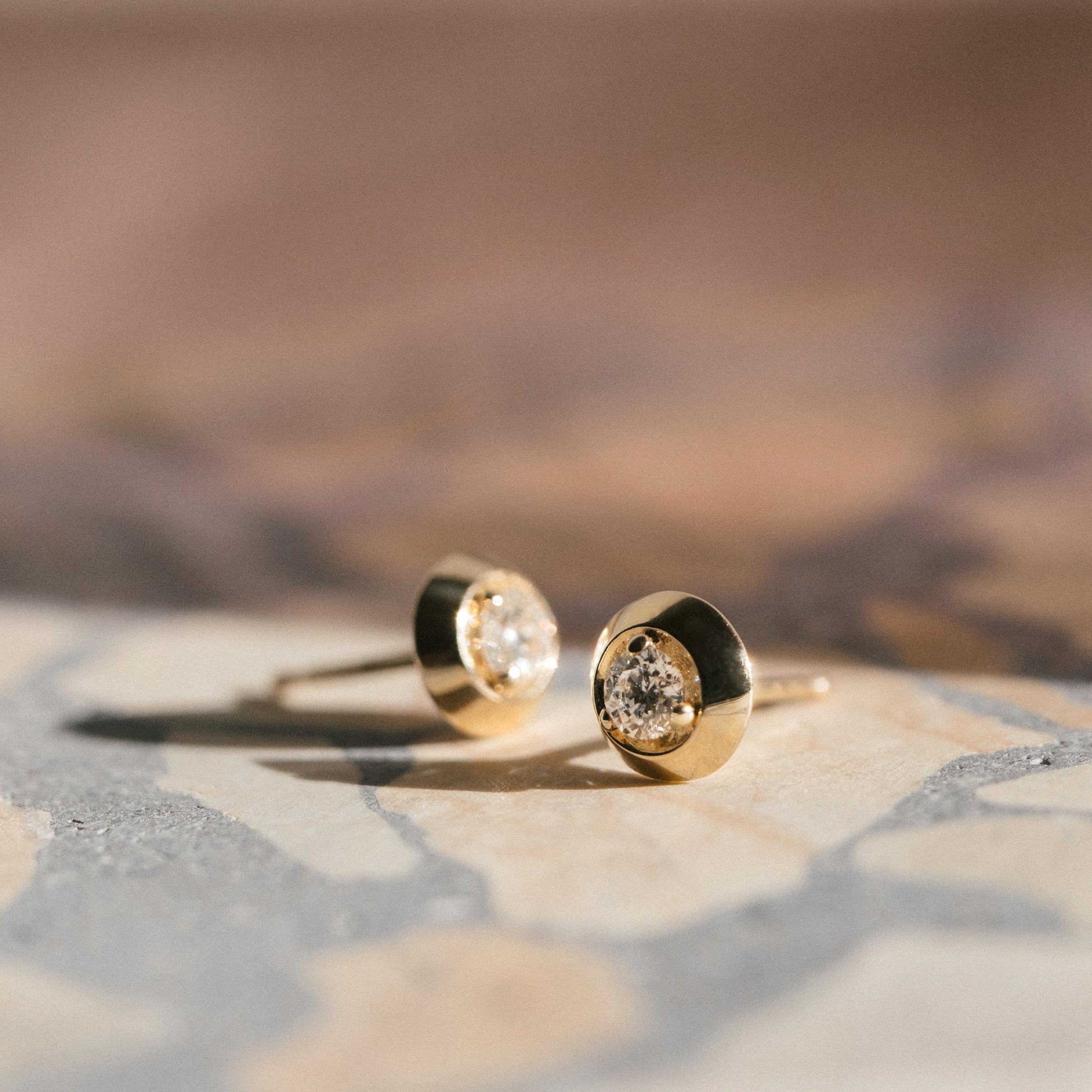 The Formation Circle Stud earrings in 14k gold fold inward reflecting a 3mm conflict-free diamond at their center. These stud earrings are the building blocks of our Classic Transformations Collection — the foundational forms. Crafted in solid 14k