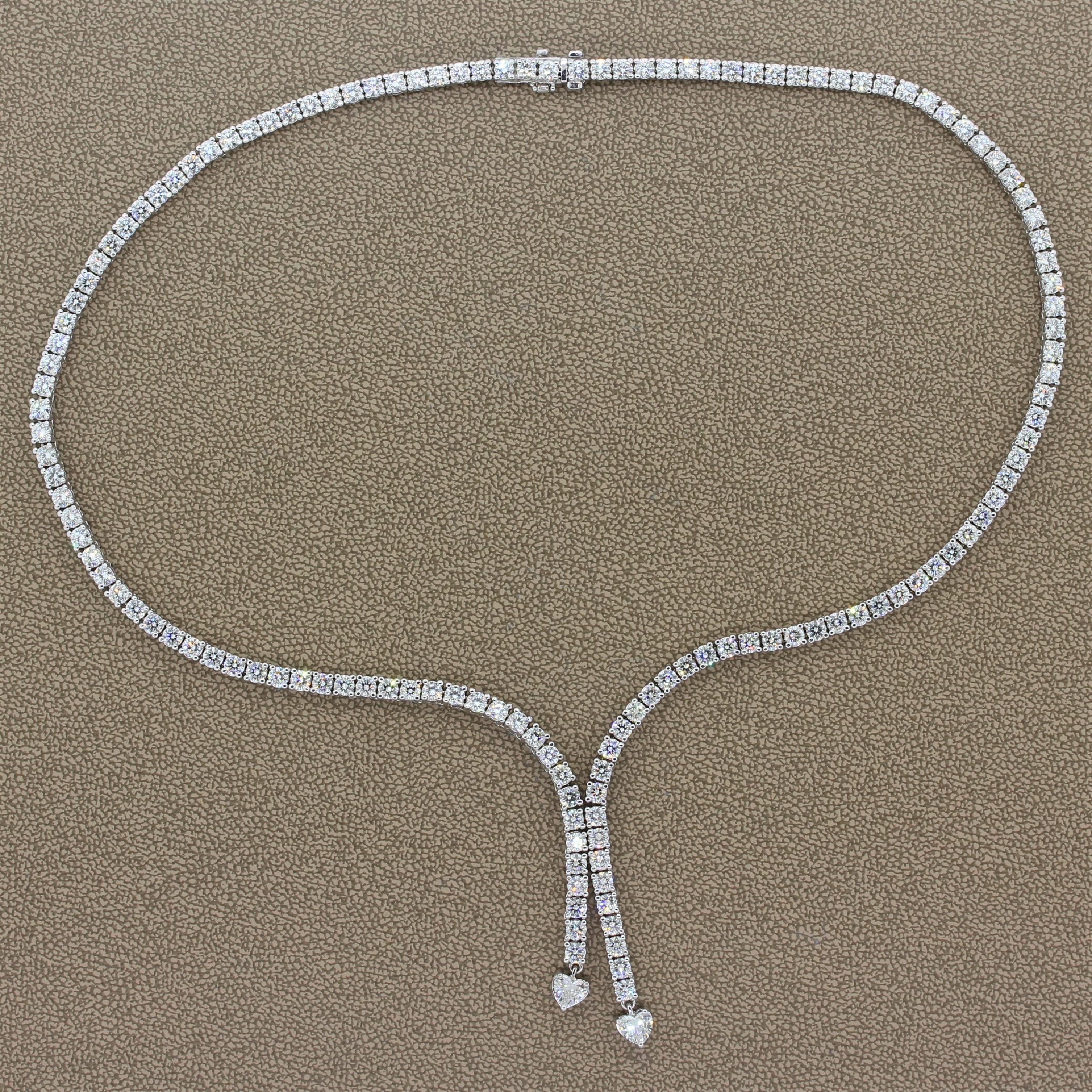 A feminine necklace with a different take on the classis tennis necklace. This sparkling necklace features 8.76 carats of VS quality round cut diamonds with two heart shape diamonds culminating the drop. The colorless diamonds are set in 18K white