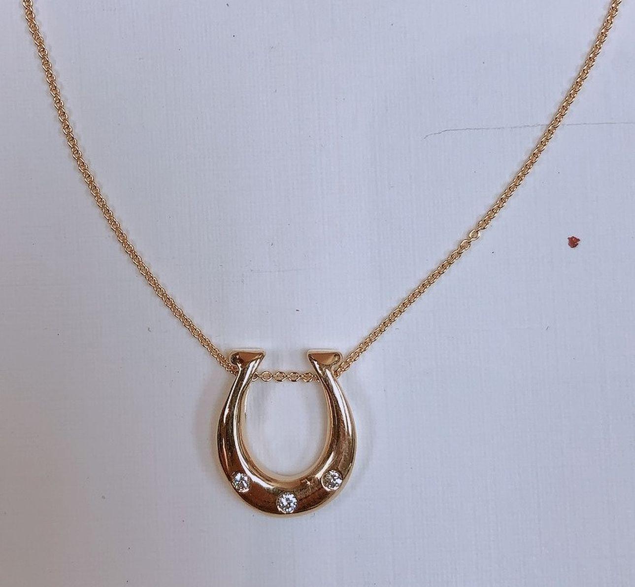 Simply Beautiful! Diamond Horseshoe Gold Drop Pendant Necklace. Hand set with 3 Round Brilliant-Cut Diamonds weighing approx. 0.17tcw. Hand crafted 14 Karat Yellow Gold mounting. Suspended from a 16” Yellow Gold chain. Pendant measures approx.