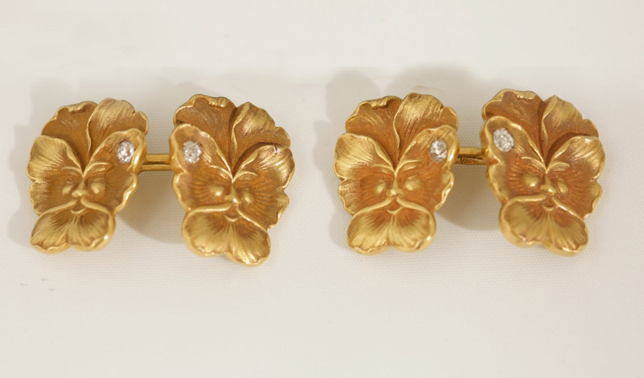 A pair of antique cufflinks from the Art Nouveau period in 14 karat yellow gold. Double sided depicting either a face or a pansy flower, set with a single diamond dewdrop. In the style of Tiffany and Co.
Measures 16mm in height x 12mm in