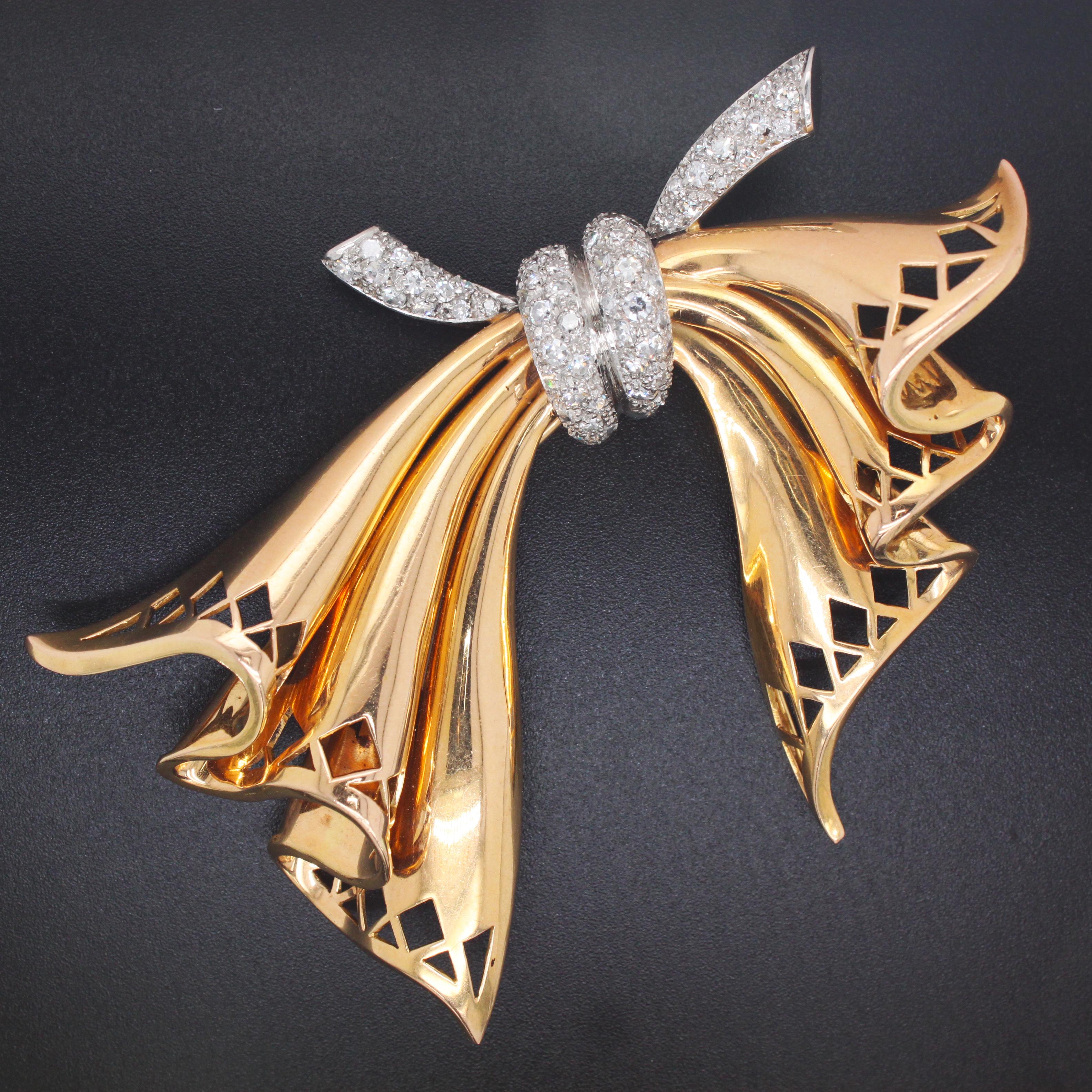 A big diamond and yellow gold Retro bow brooch, 1960s. The ribbons are made in gold and have a beautiful kite and triangular cut design at the respective ends. The upper portion of the bow is set with small single cut diamonds in a pavé setting. The
