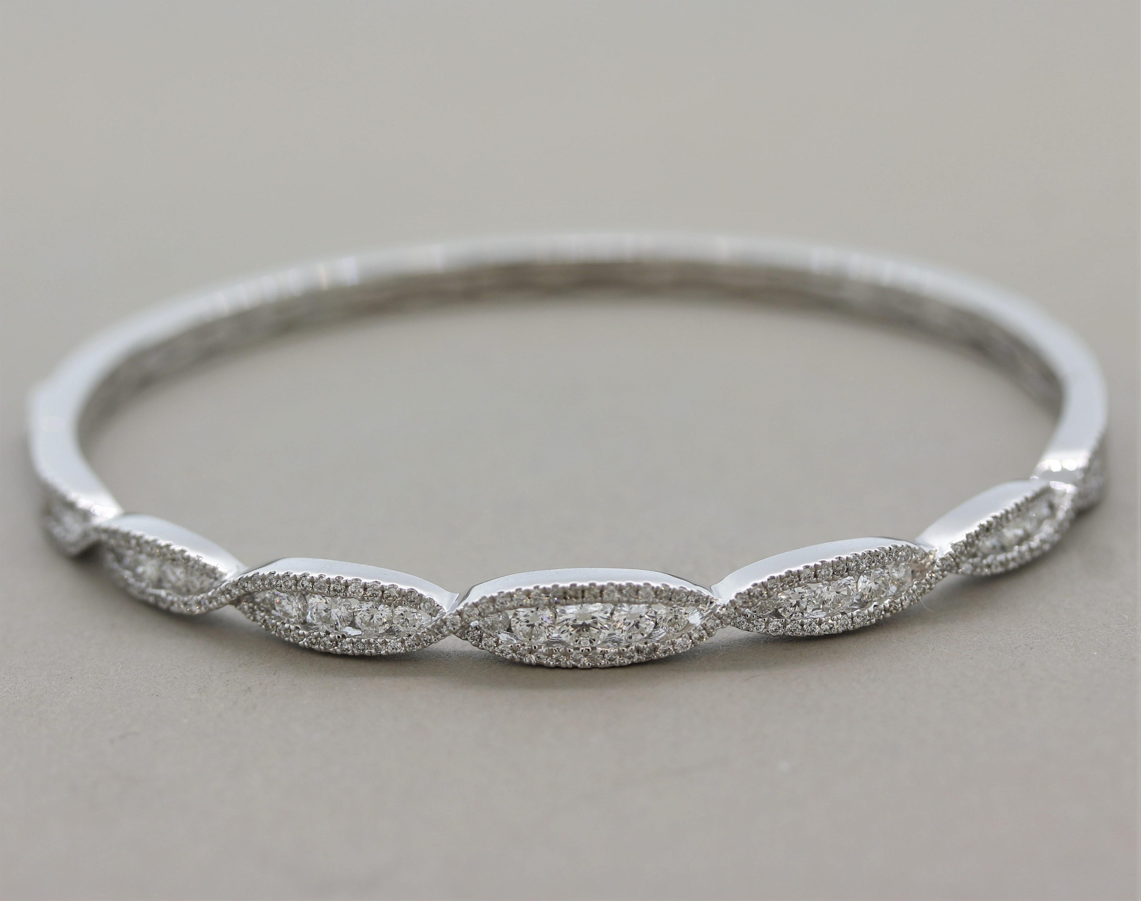 A cute and stylish bangle bracelet featuring 1.38 carats of round brilliant-cut diamonds set in a swirling pattern over the top portion of the bangle. There are larger diamonds in the center with smaller diamonds swirling on their outsides. Made in