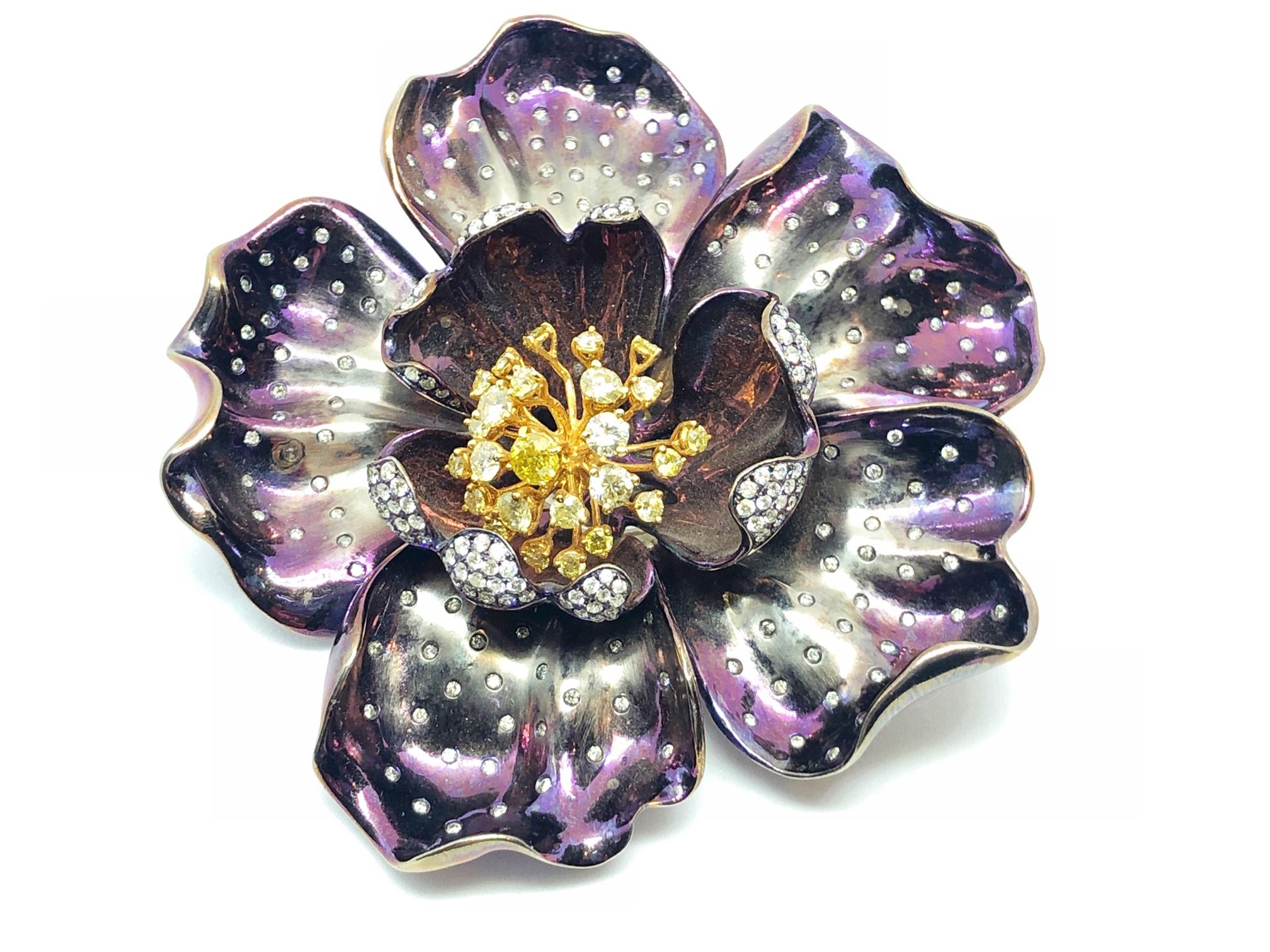A purple flower brooch, mounted in titanium, with shaded purple to silver outer petals, with purple centre petals, set with white and yellow diamonds, with a total weight of 3.76ct, with an 18ct white gold pin.