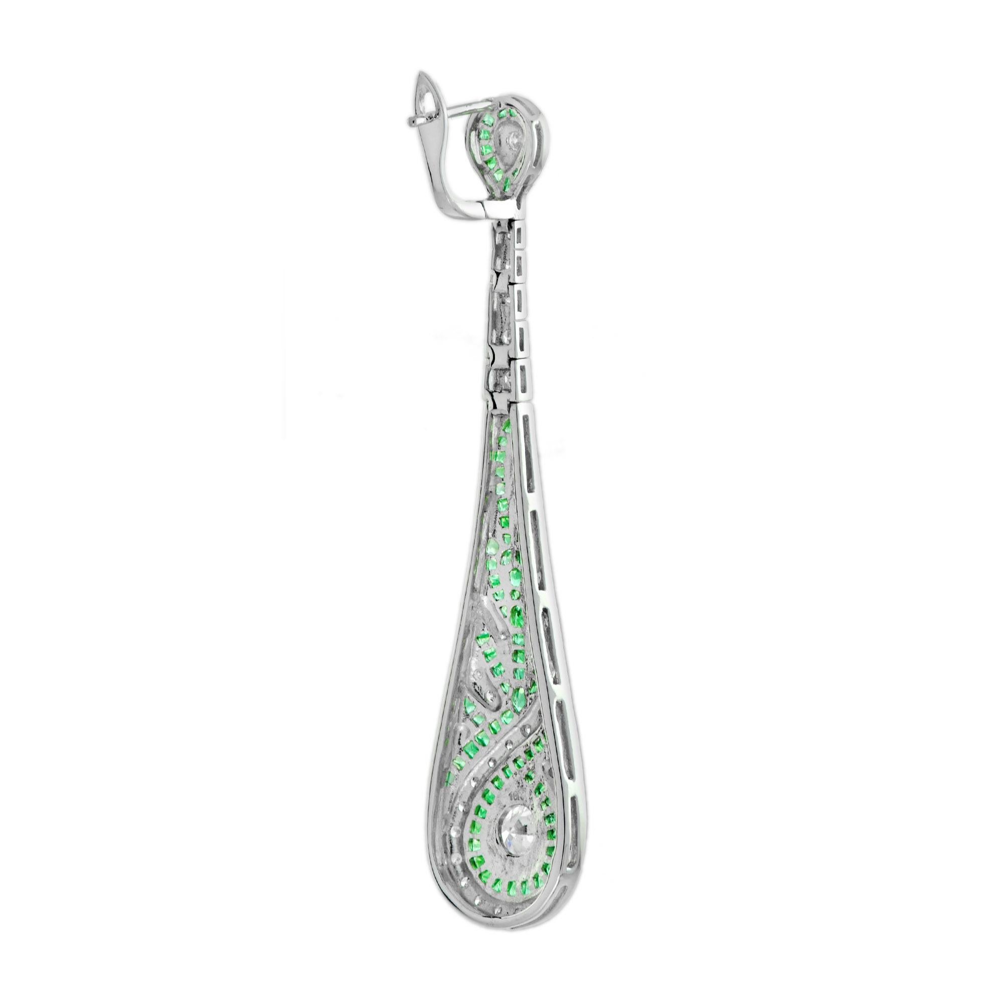 These fabulous Art Deco style ear drops, fabricated, are stunning. Measuring 63 mm. long, a pair of bright and shining old cut diamonds together weighting 0.80 carat, each ornamented with smaller diamonds bordered by French cut emeralds. 14K White