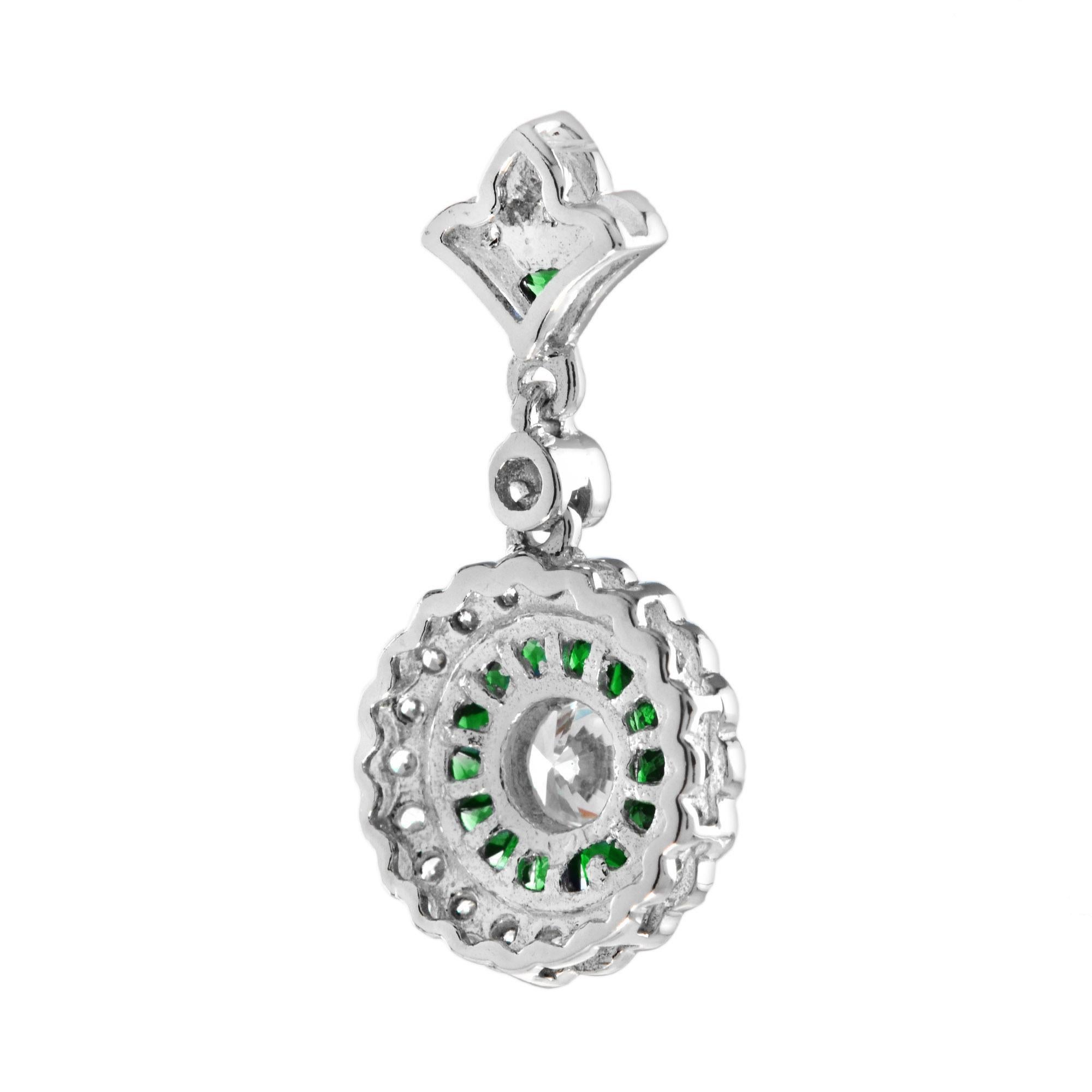 An Art Deco style diamond and emerald pendant. The center diamond is a 0.25 Carat round cut of exceptional brightness. It is surrounded by custom but emeralds that are cut by hand to fit seamlessly together. The emeralds are further enhanced by a