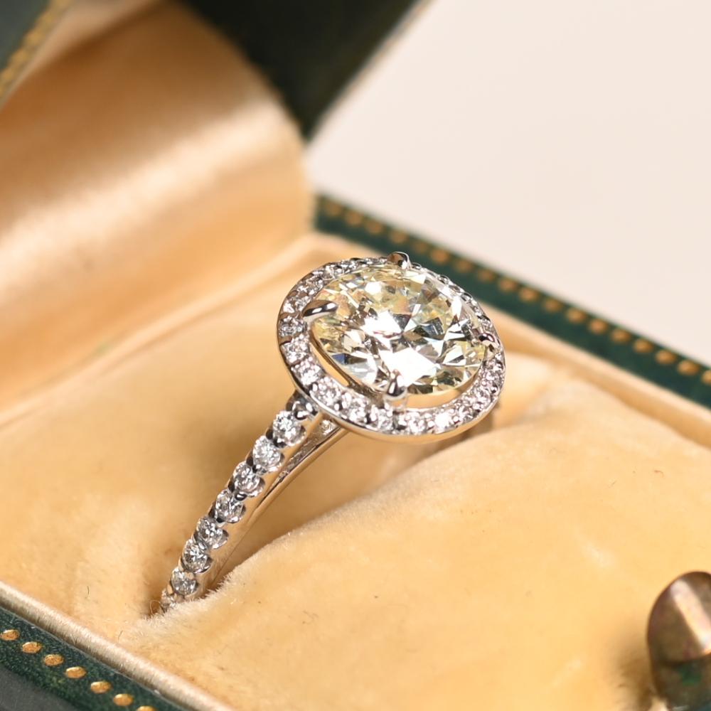 Este exquisito Anillo Halo de Diamantes de platino exhibe una elegancia atemporal y una artesanía experta, con un cautivador diamante de talla europea antigua en su centro. La piedra principal, engastada para conseguir el máximo brillo, pesa
