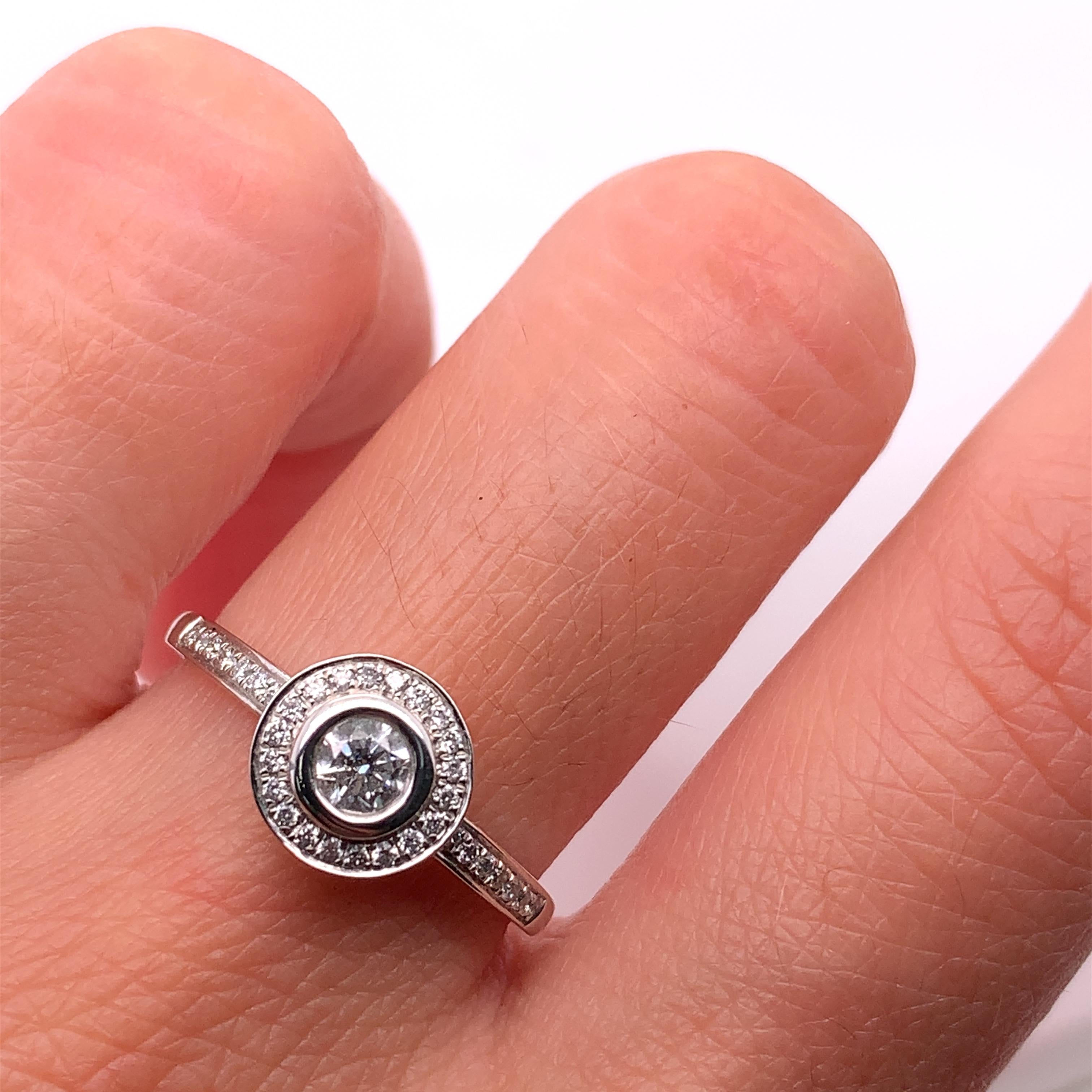 This beautiful ring features a stunning solitaire halo design with a total carat weight of 0.45ct. The main stone is a natural round diamond with an excellent cut grade and a G colour grade. The diamond is set in 18ct white gold with a band width of