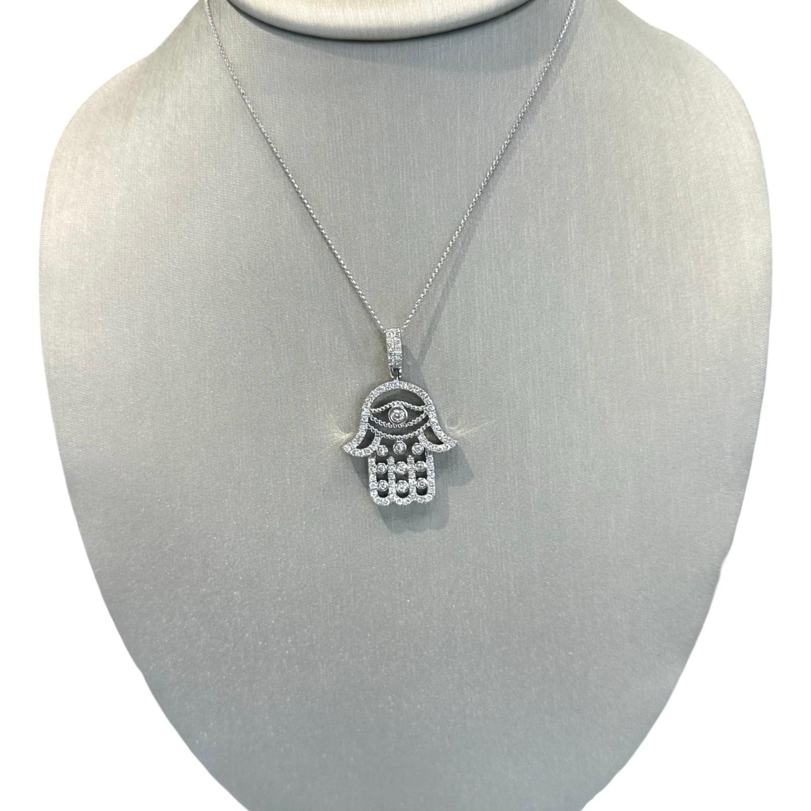 This stunning Diamond Hamsa Evil Eye Pendant Necklace is crafted from 18K White Gold and features a micro Portuguese link chain. The pendant itself is adorned with 1.5 carats of diamonds, for a total weight of 11.7g. This piece is the perfect