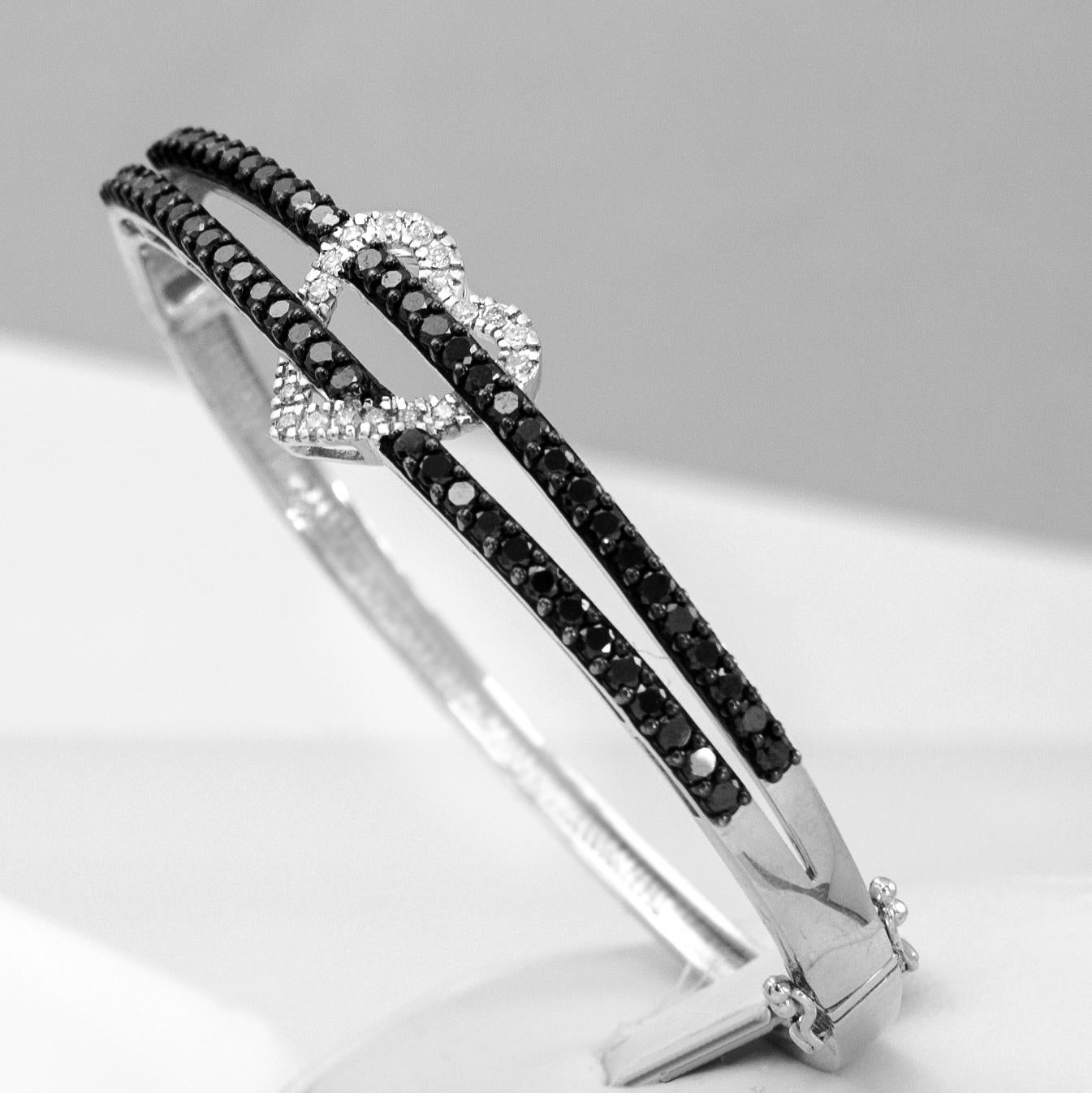 This lovely heart bangle bracelet looks fantastic everyday. Designed in sleek 14 karat white gold with 1/4 carat of white diamonds and 2.35 carats of black diamonds. This gorgeous women's bangle is available in stock. It is in size 7.