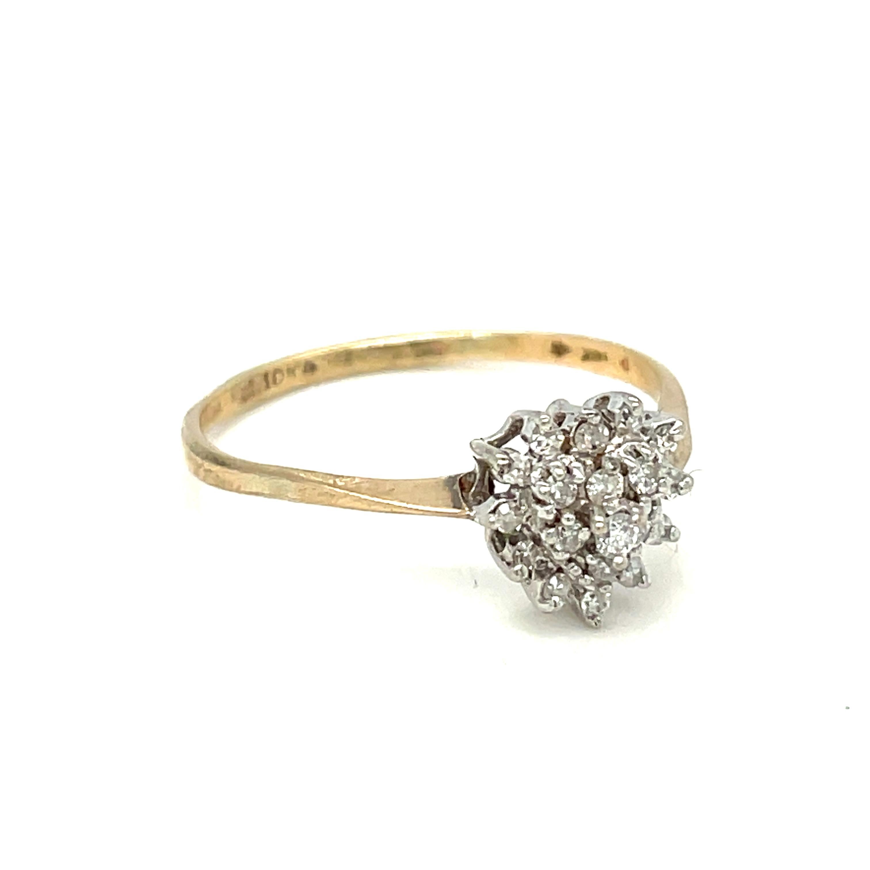 Beautiful vintage heart-shaped diamond cluster ring! Crafted from 10 karat solid yellow and white gold, the ring features a heart-shaped cluster of nineteen round brilliant cut diamonds set on three tiers in a lovely white gold basket setting. The