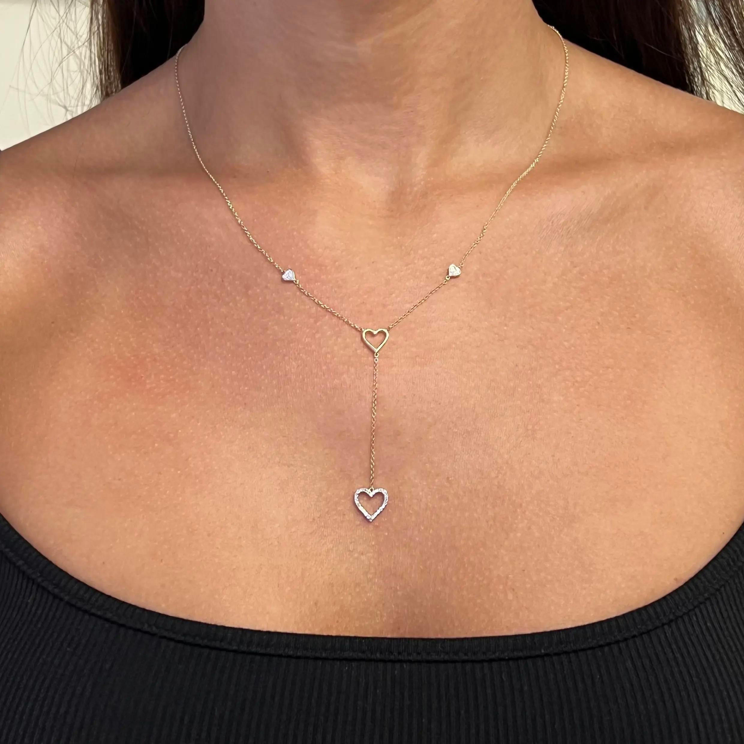 Beautiful and delicate this diamond lariat necklace will leave everyone speechless the moment they see it. Crafted in high polished 14K yellow gold. It features two pave set diamond studded heart shape motifs with a heart cut out in the center,