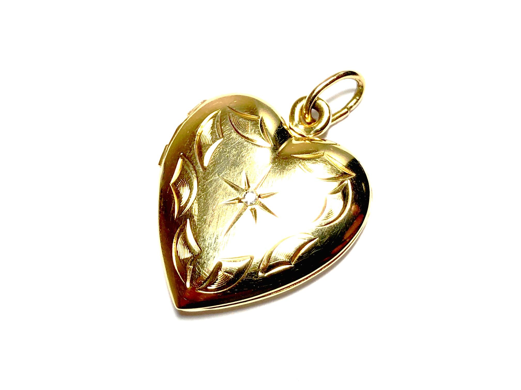 A 14ct gold heart locket, set with a central single cut diamond in a star setting, with engraved detail surrounding, opens to hold two pictures, measures 28 x 20mm including bail, circa 1990's