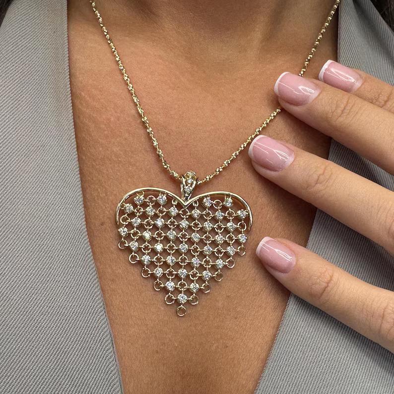 Réalisé en or 14 carats, cet exquis pendentif en forme de cœur présente un délicat motif de maille orné de 39 diamants ronds de taille brillant totalisant 1,43 carats, de couleur G-H et de pureté VS2-SI1. Le motif en treillis ajouré crée un