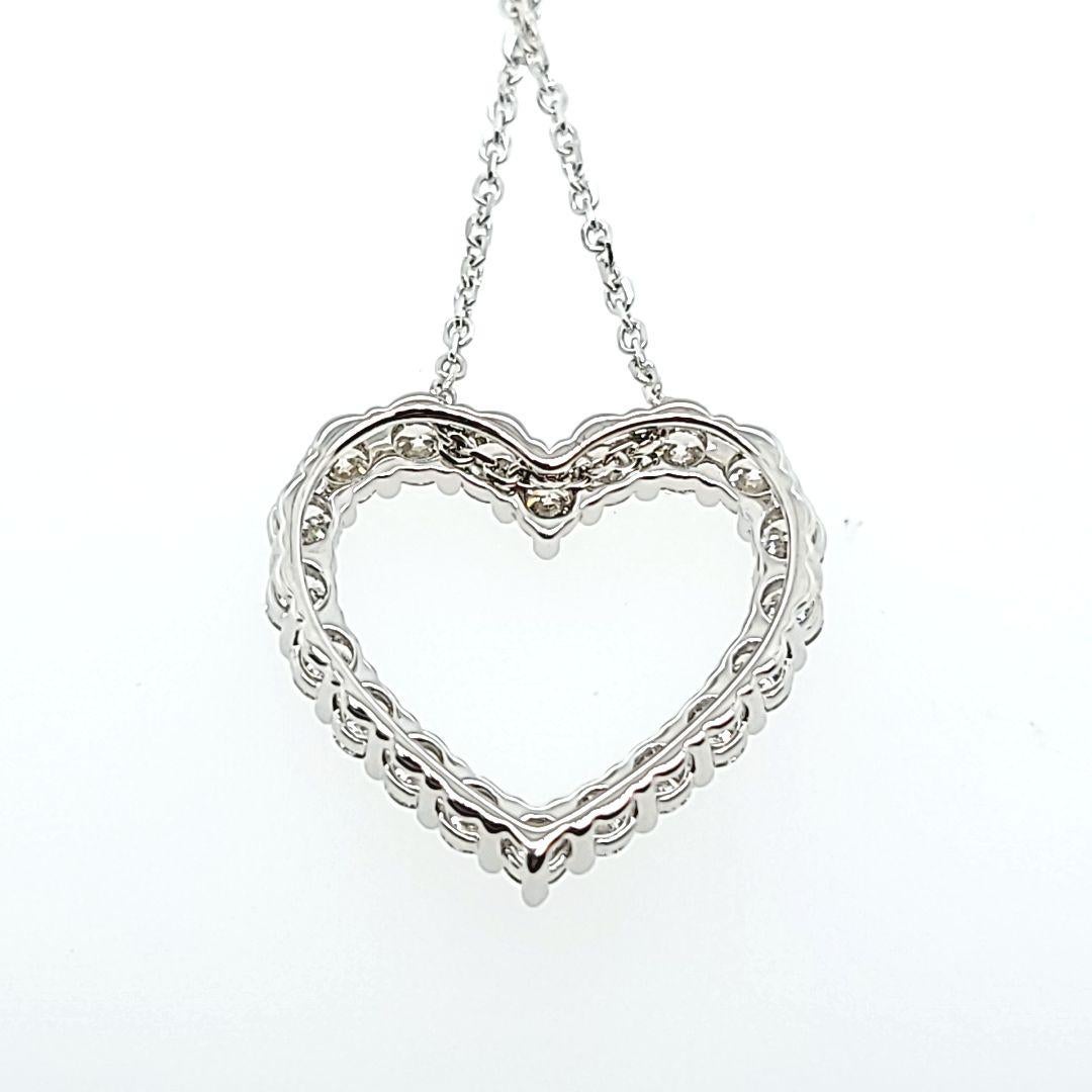 14 Karat White Gold Heart Pendant Necklace Featuring 20 Prong-set Round Brilliant Cut Diamonds of VS Clarity and G Color Totaling Approximately 1.00 Carat. Adjustable Length 17-18 Inch Chain with Lobster Clasp. Finished Weight Is 3.4 Grams.