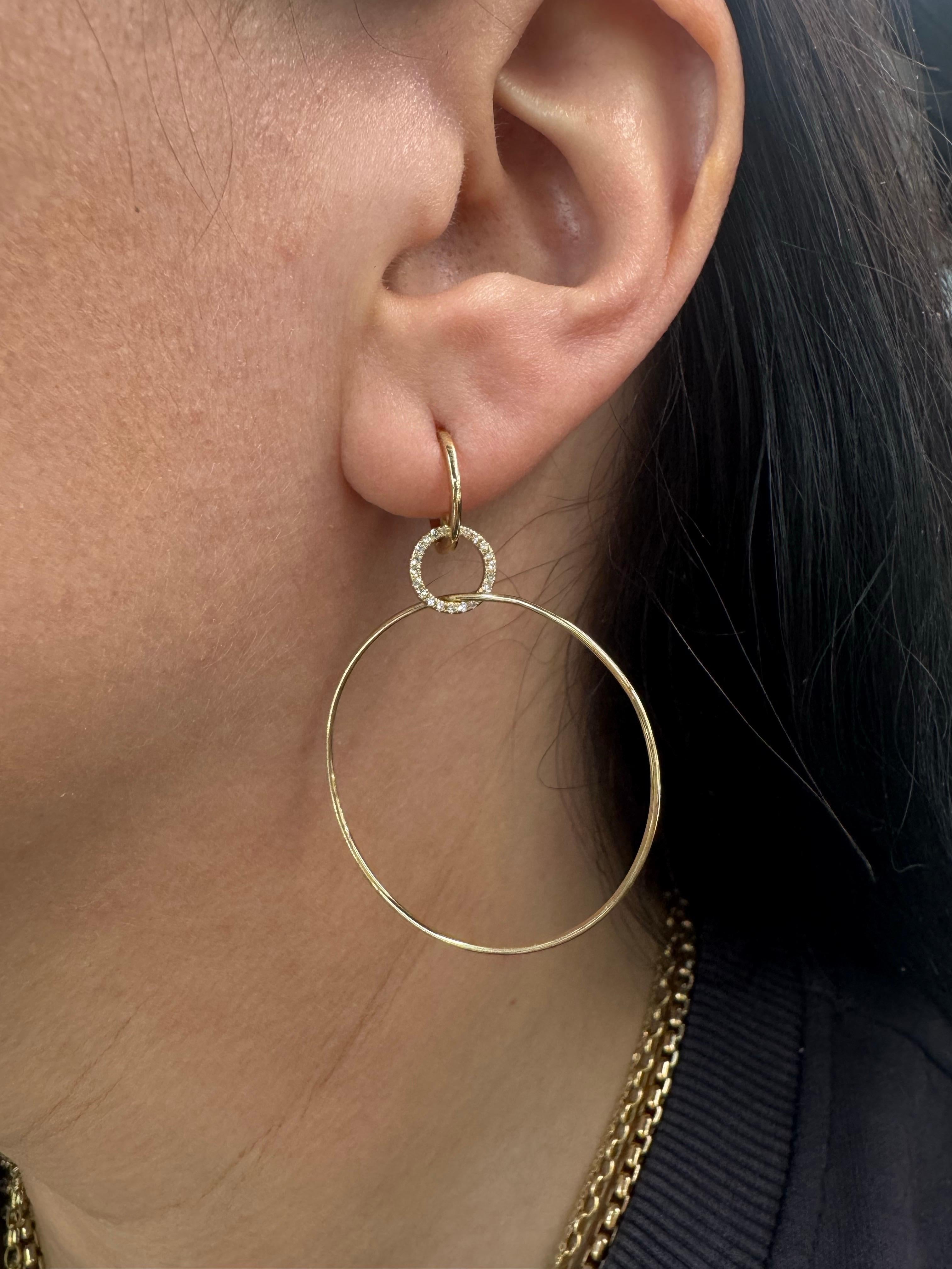 These 14K gold hoop drop earrings blend minimalist design with a hint of sparkle for a look that’s chic yet understated. A shimmering diamond-encrusted circle anchors a lightweight, open gold oval hoop, creating fluid movement and timeless
