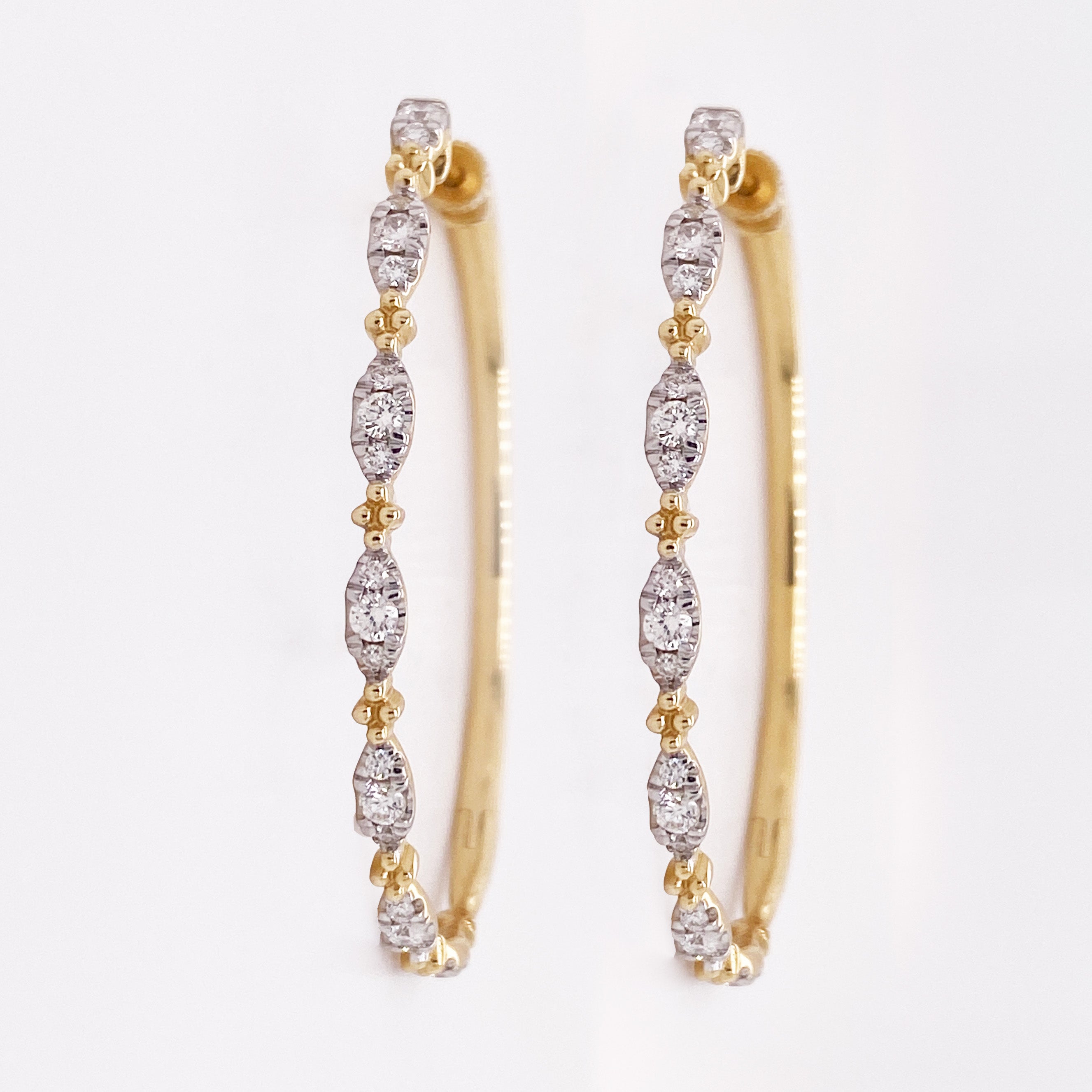 These two-tone Gabriel & Co. hoops are gorgeous and SO wearable! Diamonds in white gold alternate with small yellow gold quatrefoil clusters on these 1.57 inch long ovals for a contemporary look on a classic hoop design. They can be worn with any