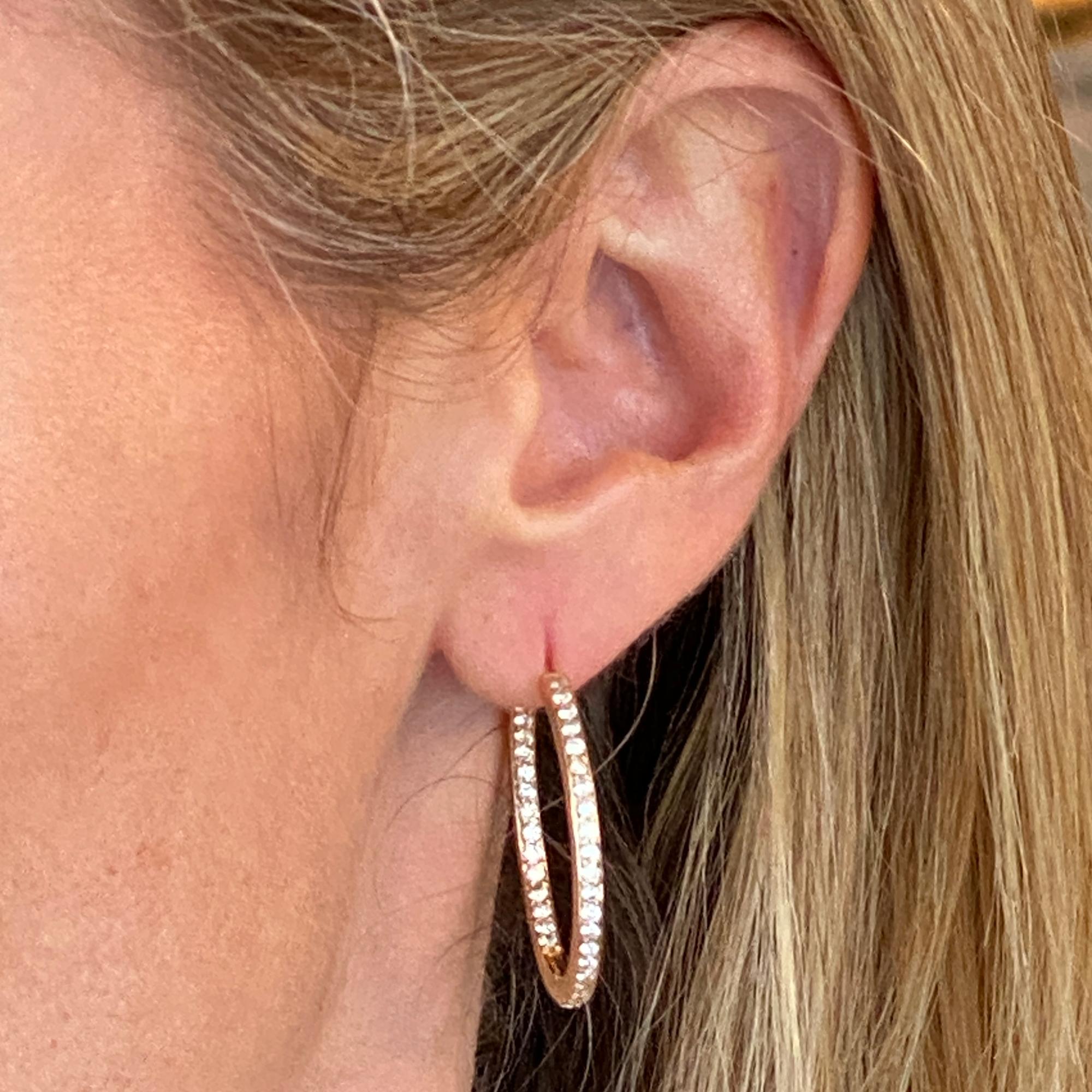 Great everyday diamond hoop earrings fashioned in 14 karat yellow gold. The earrings feature round brilliant cut diamonds weighing 1.76 carat total weight and graded G-H color and SI1 clarity. The light weight hoops measure 1.25 inches in diameter,