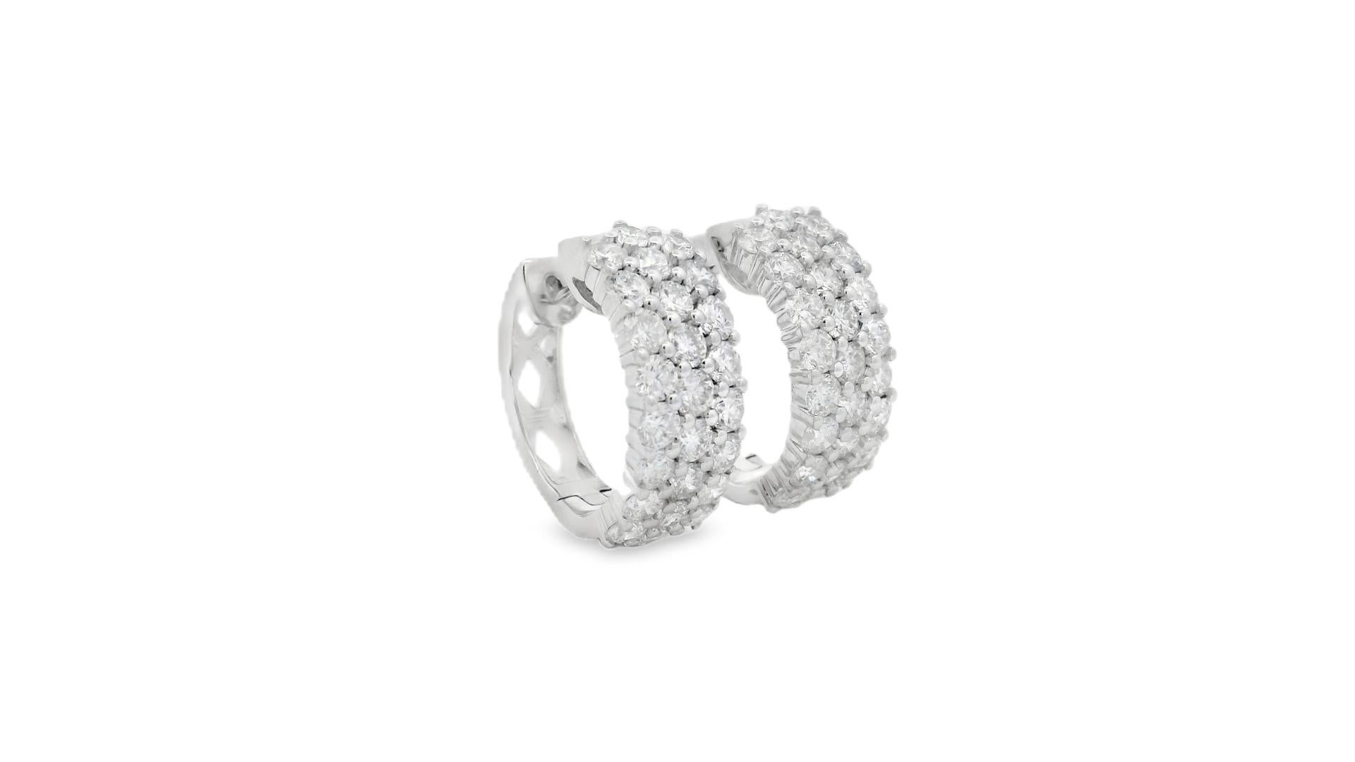 Timeless and radiant, these 14K white gold hoop earrings are encrusted with 50 round brilliant-cut diamonds totaling 4.00 carats. Designed with an inside-out setting, the diamonds are visible from both the front and the interior, ensuring a