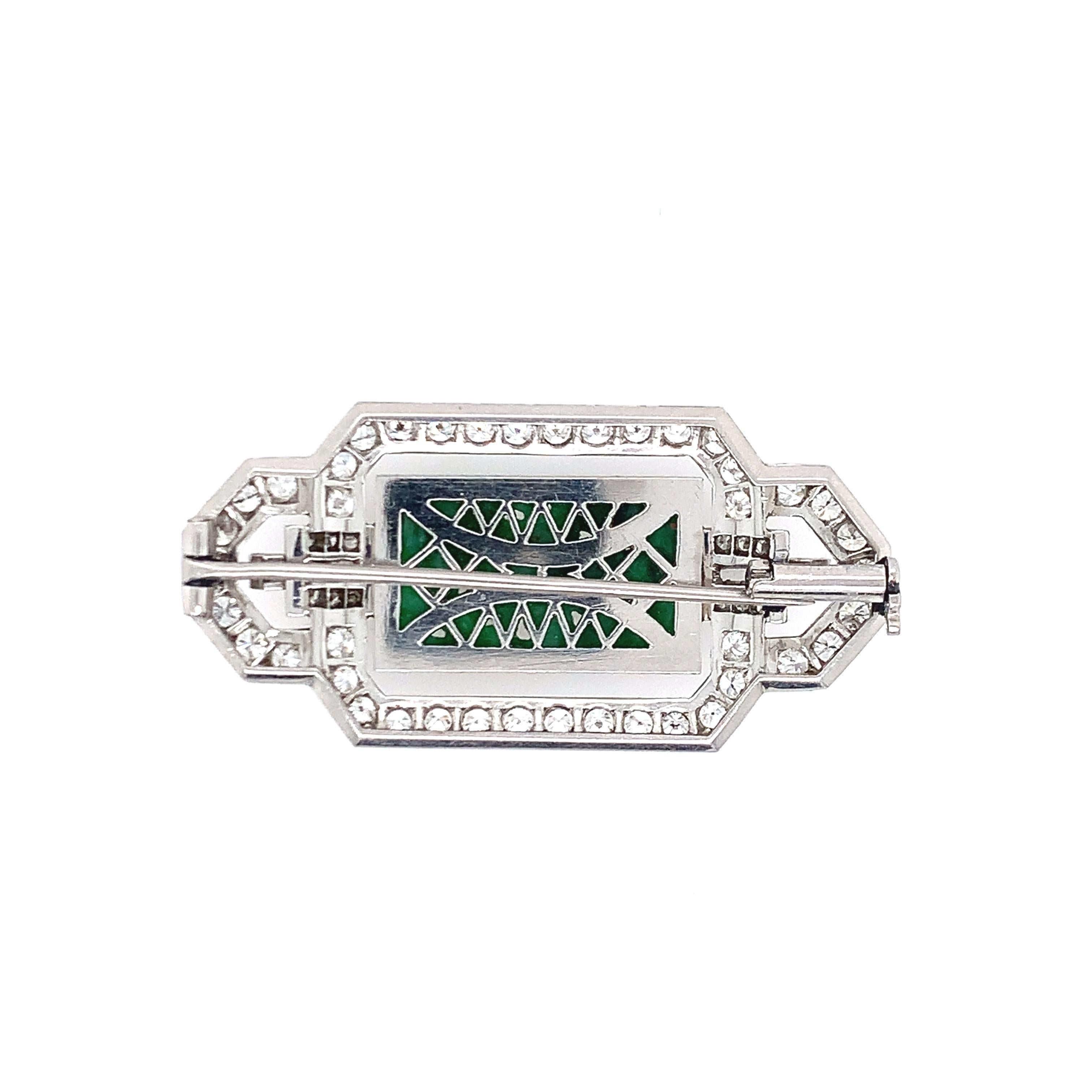 An art deco style brooch, this piece is set in platinum, consisting of approximately 3.5 carat diamonds with natural, type A jade at the center. The length is 0.88 inch and the width is 1.88 inches. The total weight is 15.7 grams. 