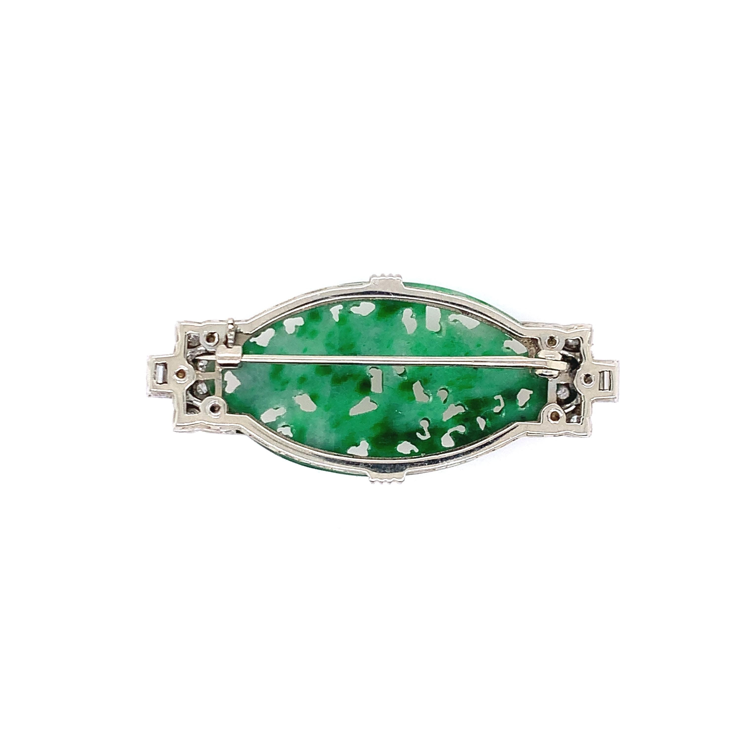 With a beautiful work of natural, type A jade at its center, this art deco brooch is set in platinum and consists of 0.50 carat diamonds. Its length is 0.88 inch and its width is approximately 2 inches. The total weight is 12.3 grams. 