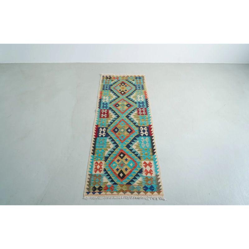 Cette coureuse en laine Kilim diamantée présente un motif géométrique aux couleurs vives, évoquant le paysage montagneux du col de Khyber où elle a été tissée pour être aussi durable que belle.

Le tissage de tapis occupe une place essentielle