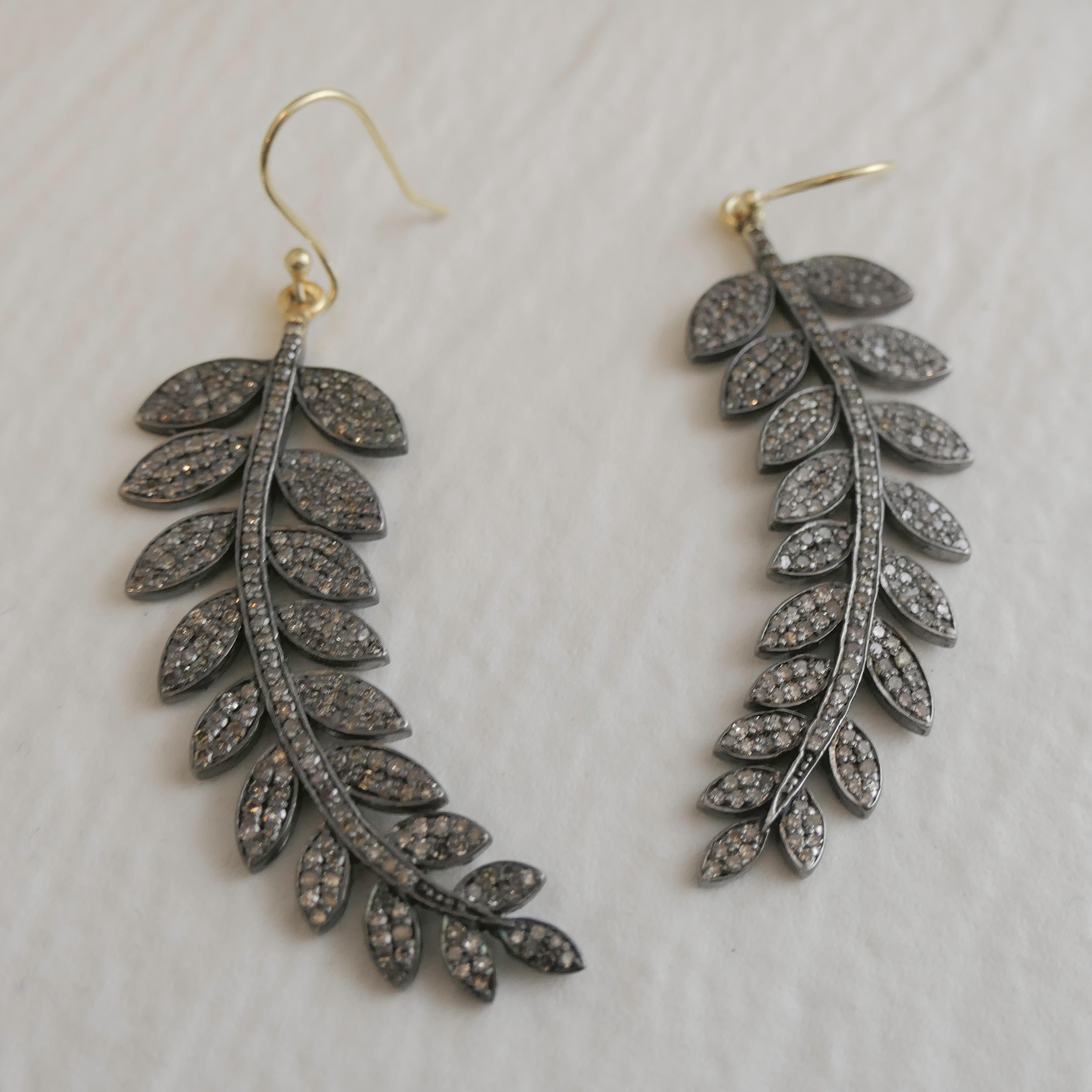 Piccoli diamanti in pavé sono incastonati nell'argento sterling ossidato e montati su fili d'argento placcati oro. La lunghezza degli orecchini è di 6,8 cm.
