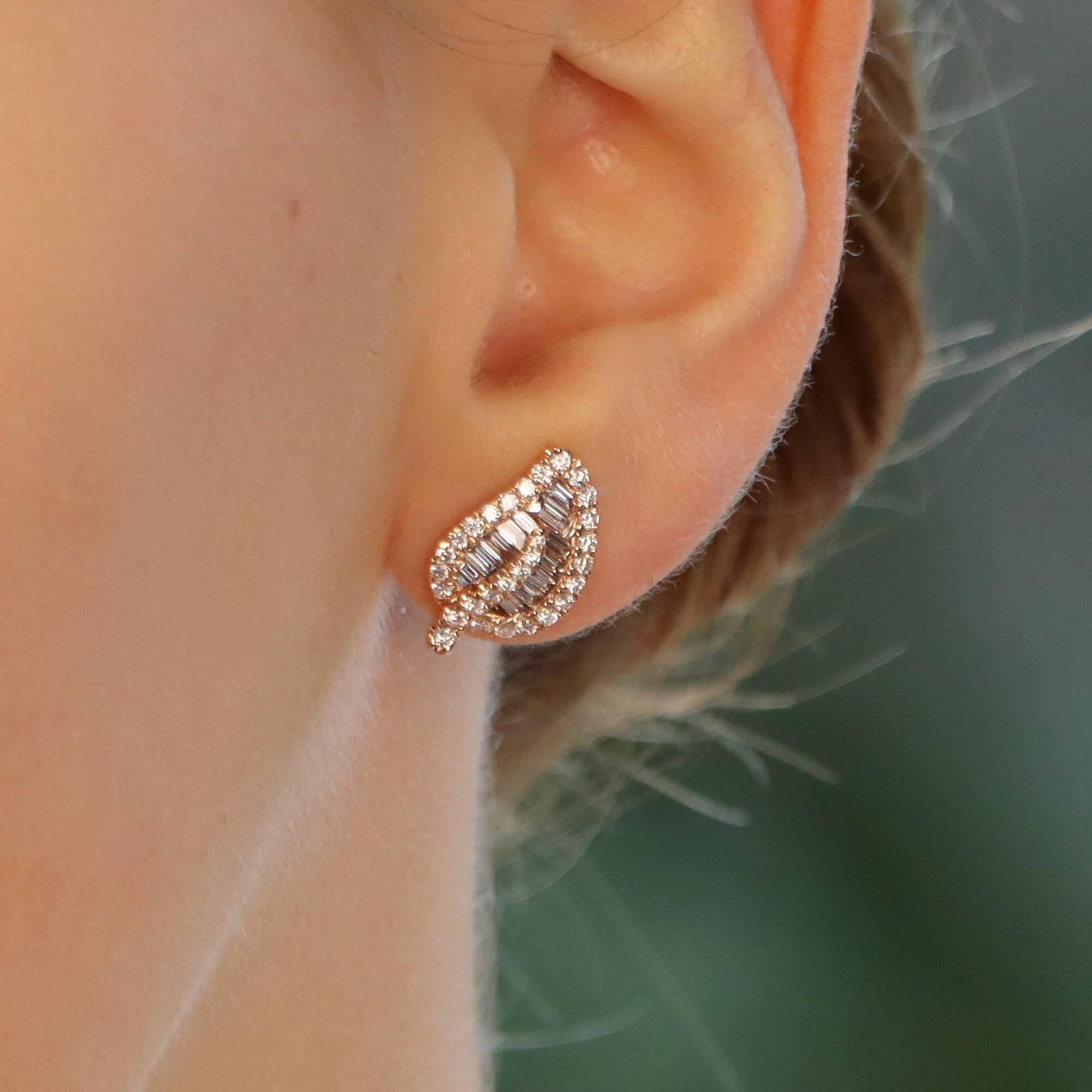 Un bellissimo paio di orecchini a foglia di diamante in oro rosa 18 carati. 

Ogni orecchino raffigura un semplice disegno a foglia ed è incastonato con un mix di diamanti rotondi taglio brillante e taglio baguette. Il contrasto tra i due tagli di