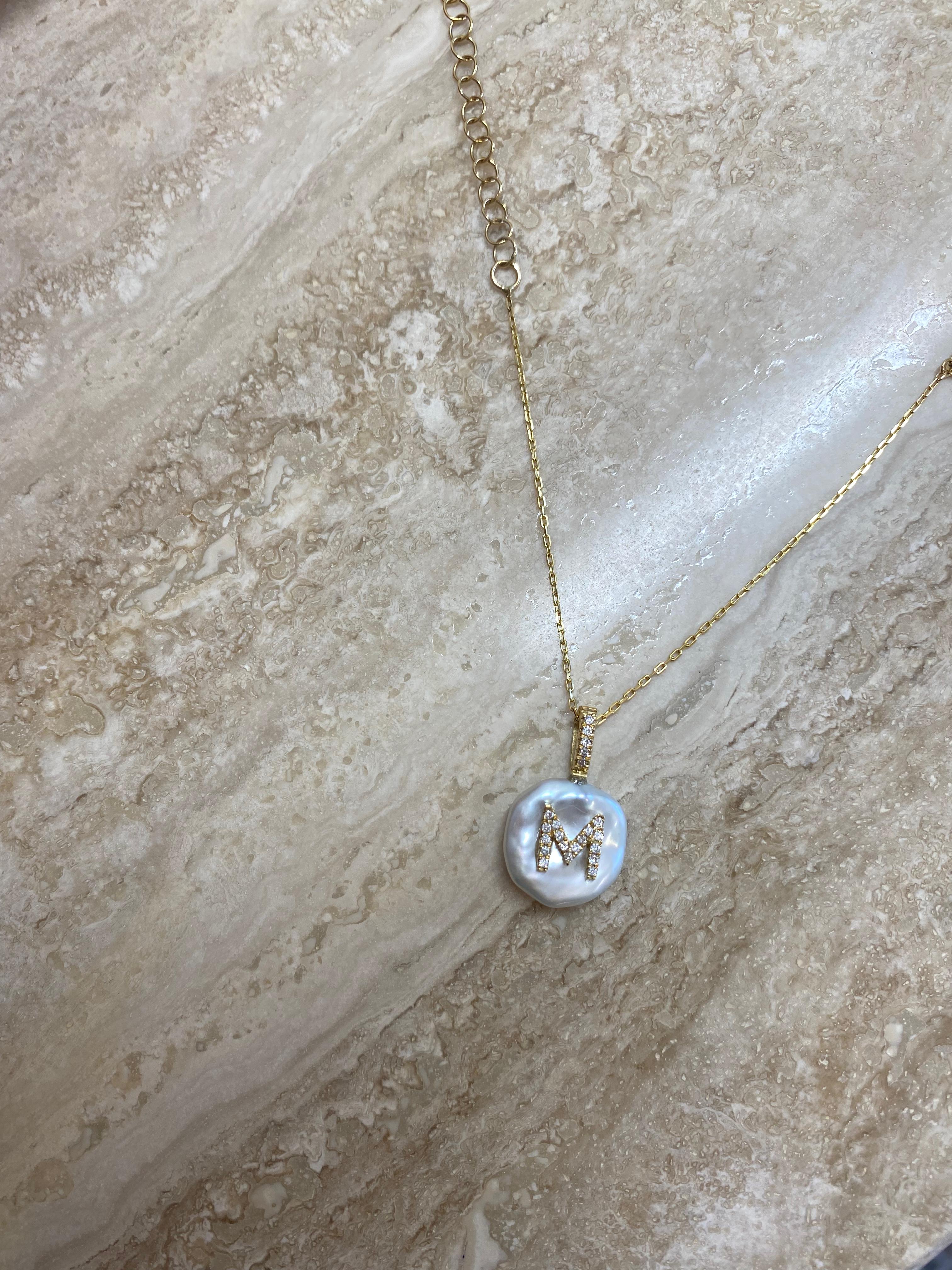 This unique pearl charm features the letter M on a freshwater keshi pearl. The initial is casted from 18Karat Yellow Gold and set with natural glimmering diamonds. 

The pearl is handpicked for its luster and one-of-a-kind beautiful appearance.