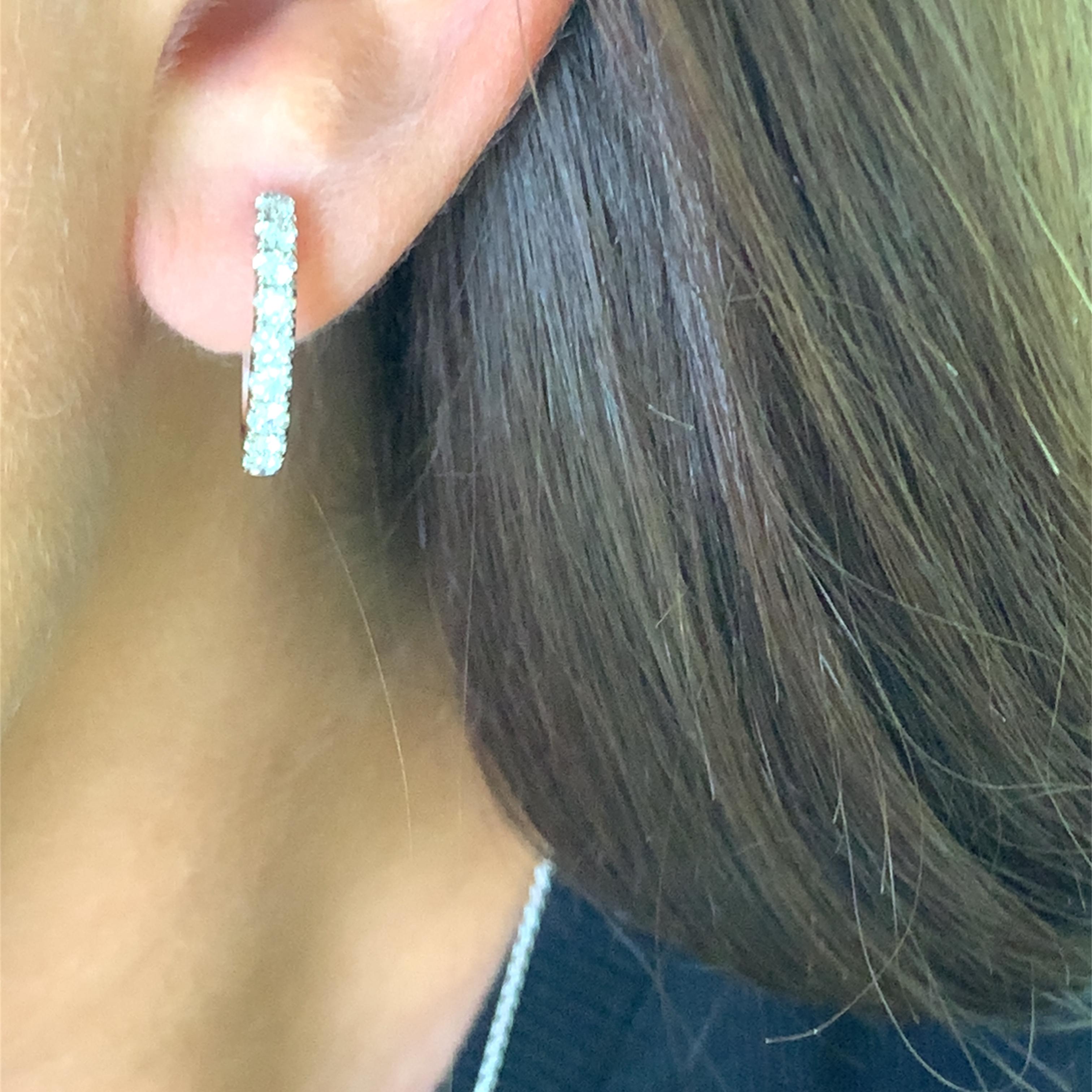 Exquisite hoop earrings crafted in lustrous 18k white gold, showcasing a dazzling array of round cut diamonds. These brilliant diamonds provide unparalleled sparkle and sophistication, making these earrings a timeless addition to any jewelry