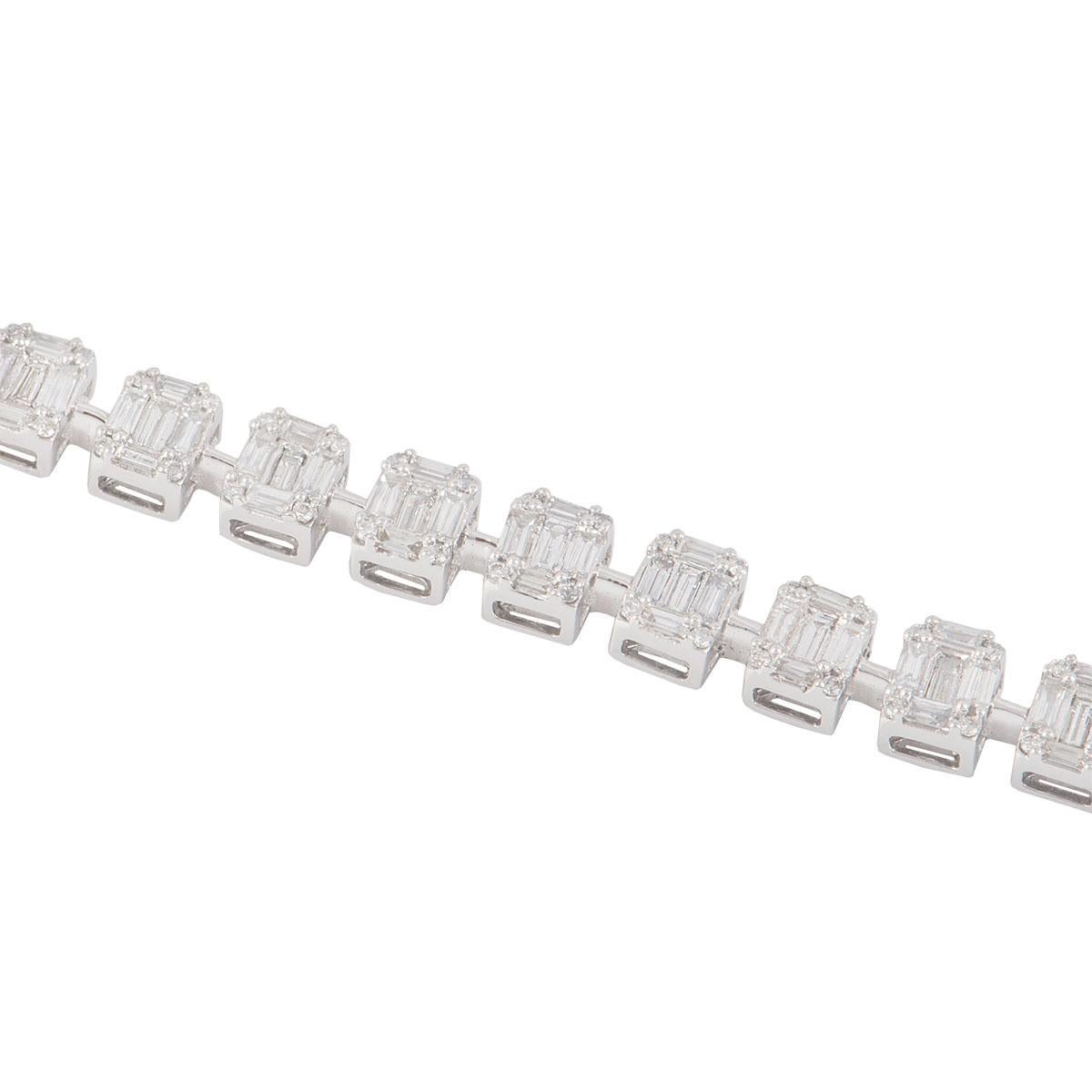 An 18k white gold illusion set diamond line bracelet. The bracelet is set with 27 rectangular mounts evenly spaced. Set with round brilliant cut diamonds in each corner, baguette cut diamonds in between and through the centre. The round brilliant