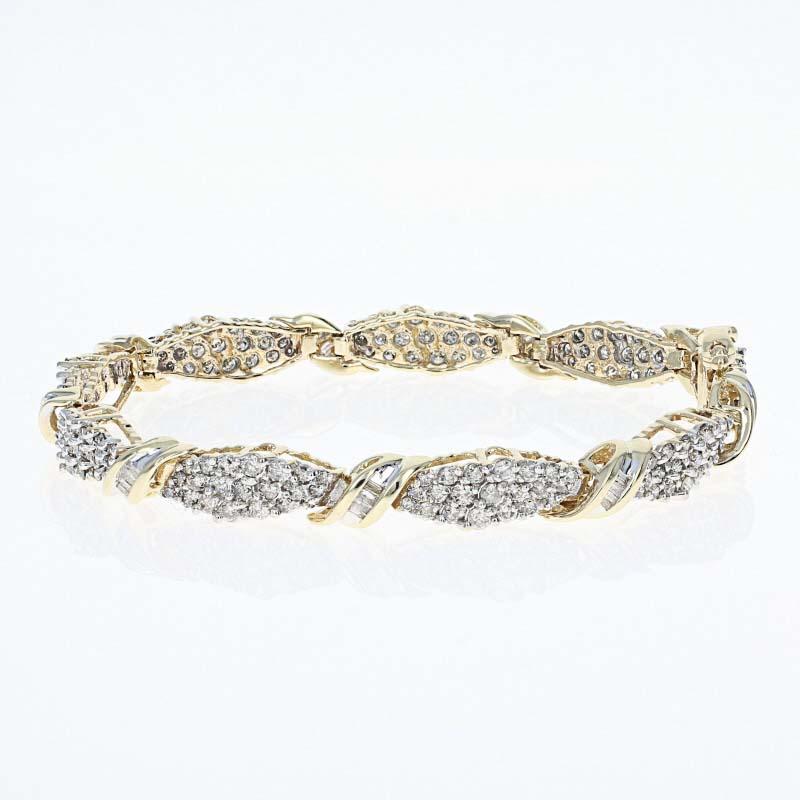 Absolutely dazzling, this bracelet will be a glorious finishing touch to pair with your little black dress! This 14k yellow and white gold link-style piece showcases icy white clusters of round cut diamonds bordered by diagonally-set baguette cut